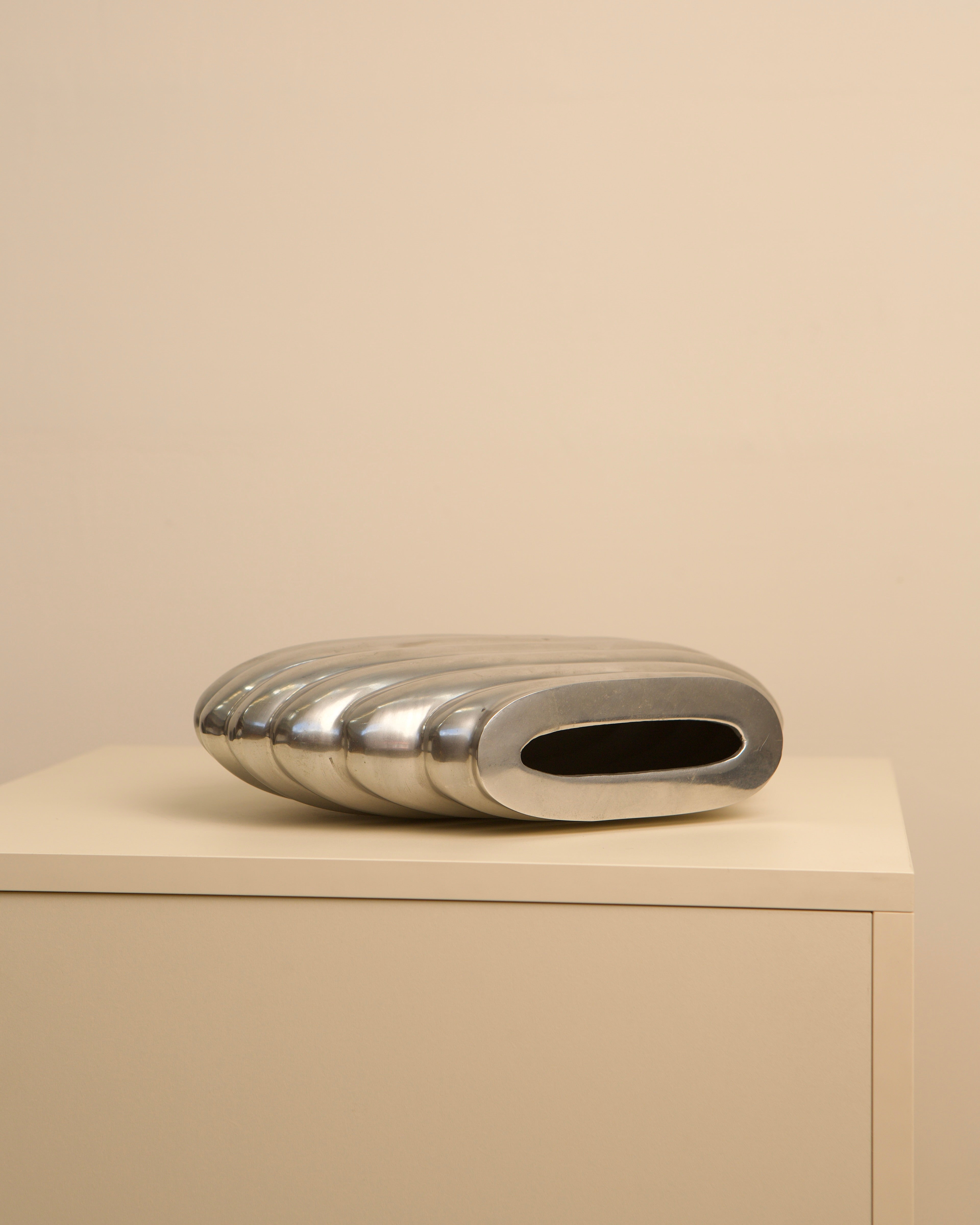 Polished aluminum oval vase with ribbed surface detail view