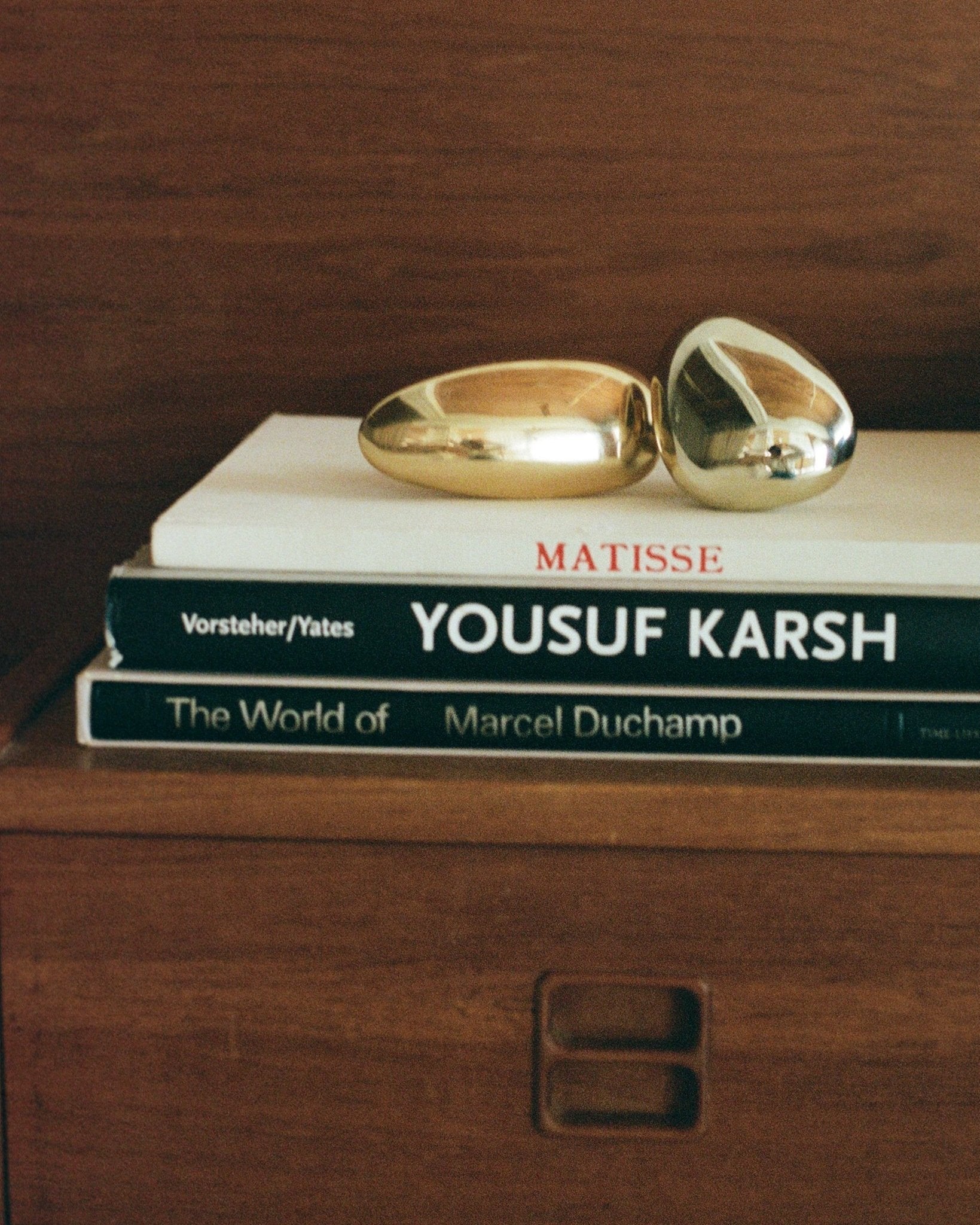 MOMI Cabinet Knob/Wall Hook Short — gold finish on stacked art books