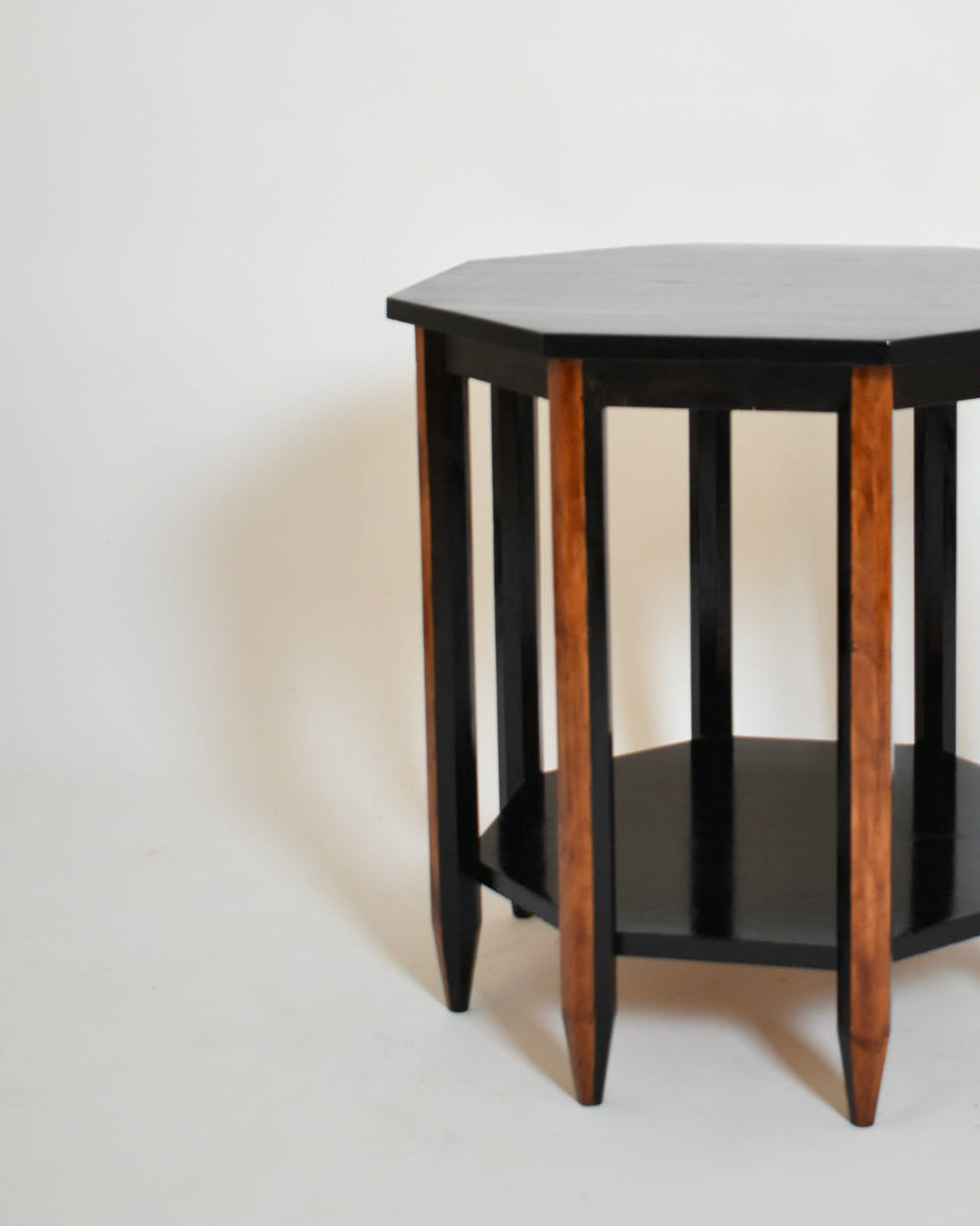 The Octogonal Modernist Side Table, 1920s by Barracuda Interiors features a black top and shelf, natural wood legs, and vertical supports, all set against a plain white background.