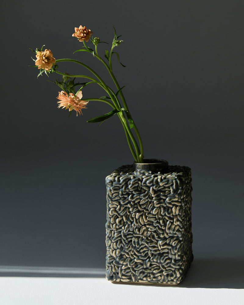 Molecules ceramic vase with textured surface holding peach flowers