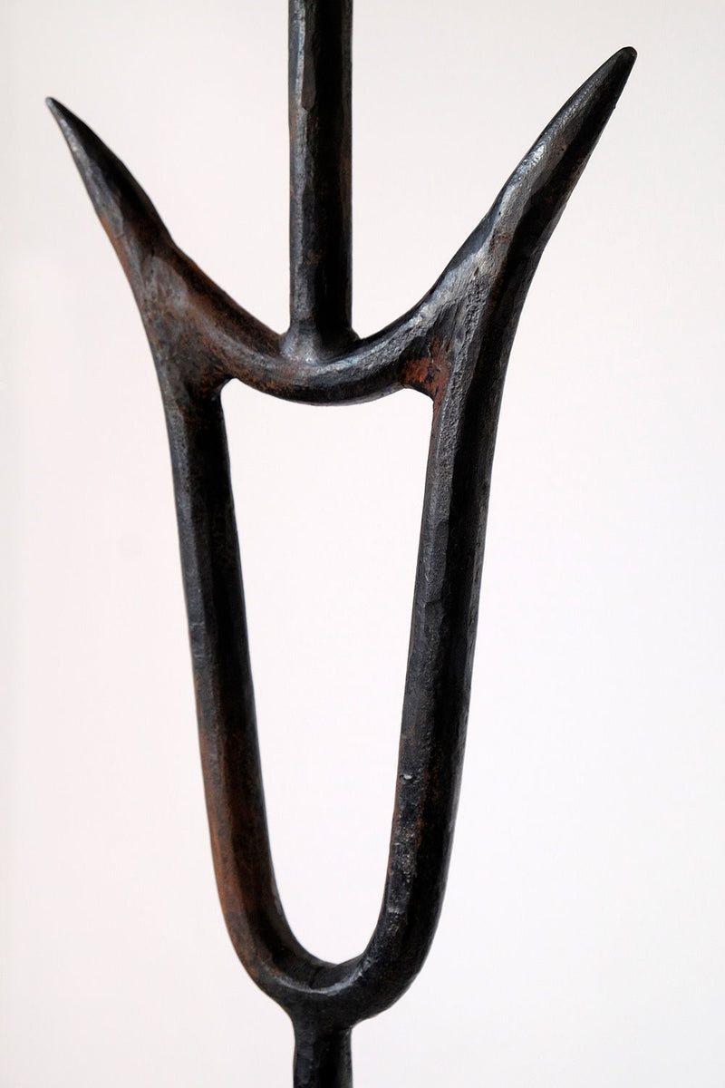 A close-up of the black iron "Sevilla" Lamp by Barracuda Interiors, featuring a U-shaped frame with two upward-facing prongs and a textured, slightly worn finish, set against a plain white background.