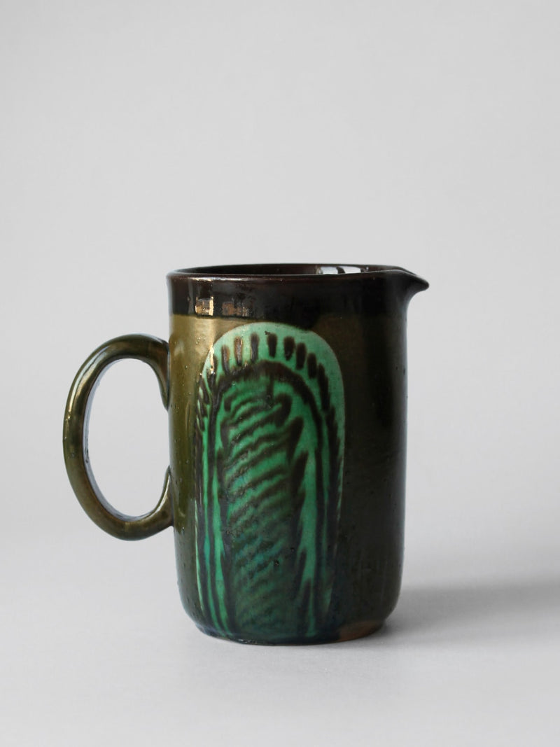 Vintage ceramic pitcher with dark green glaze and decorative pattern