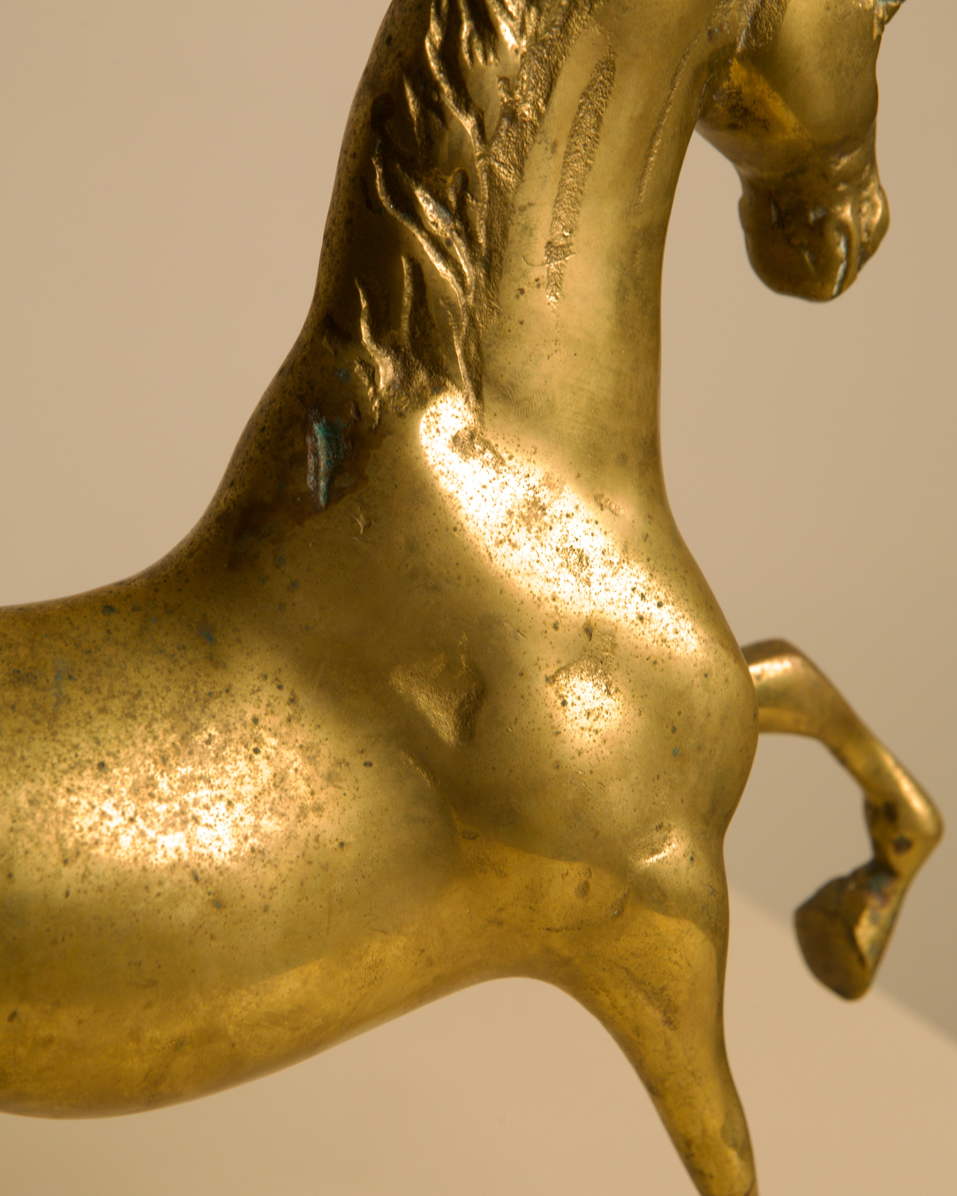 Close-up detail of golden brass horse sculpture showing texture