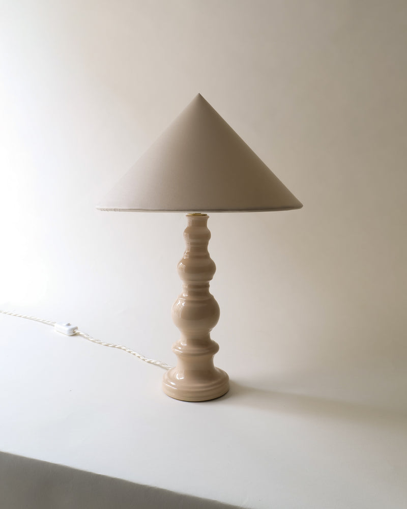 Beige ceramic table lamp with triangular shade and turned base