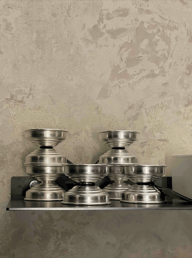Polished Metal Candle Holders in Polished aluminum — stacked on shelf against textured wall