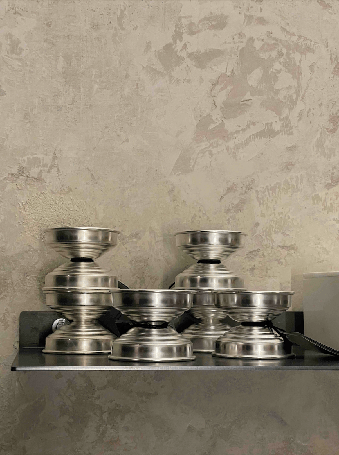 Polished Metal Candle Holders in Polished aluminum — stacked on shelf against textured wall