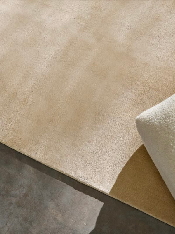 Hand-woven Rug in New Zealand Wool, Beige Sand — side angle showing soft texture on concrete floor