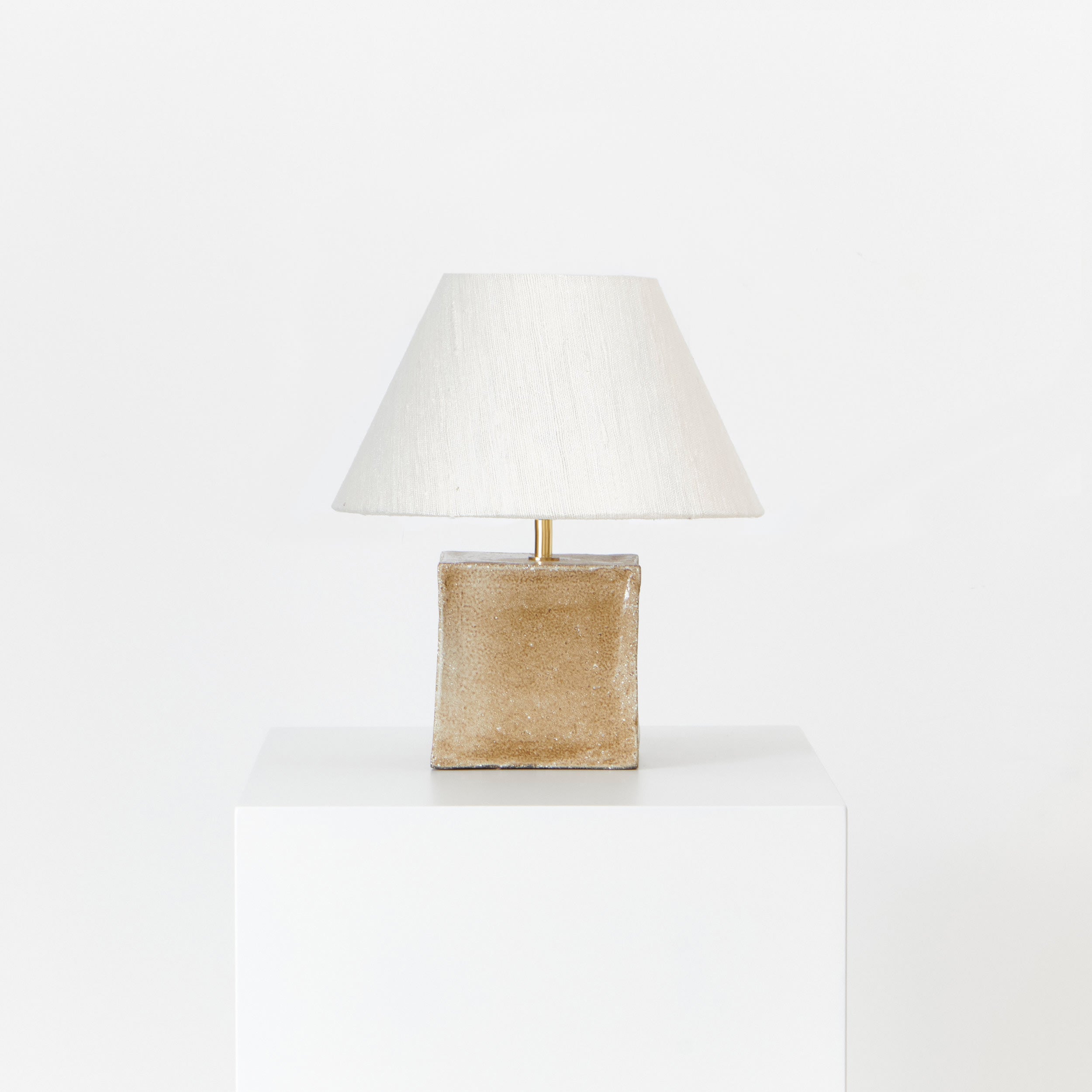 Arouca Table Light Brown Sugar — side angle of lamp on white pedestal