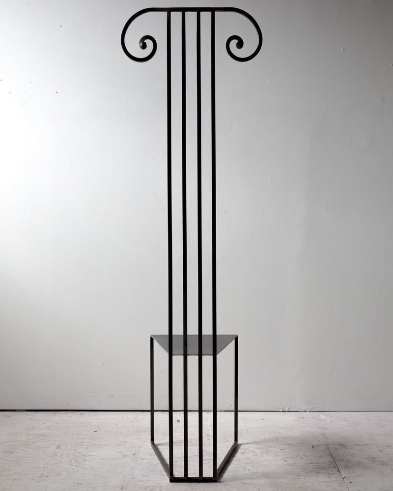 Minimalist black metal column chair with ionic capital design