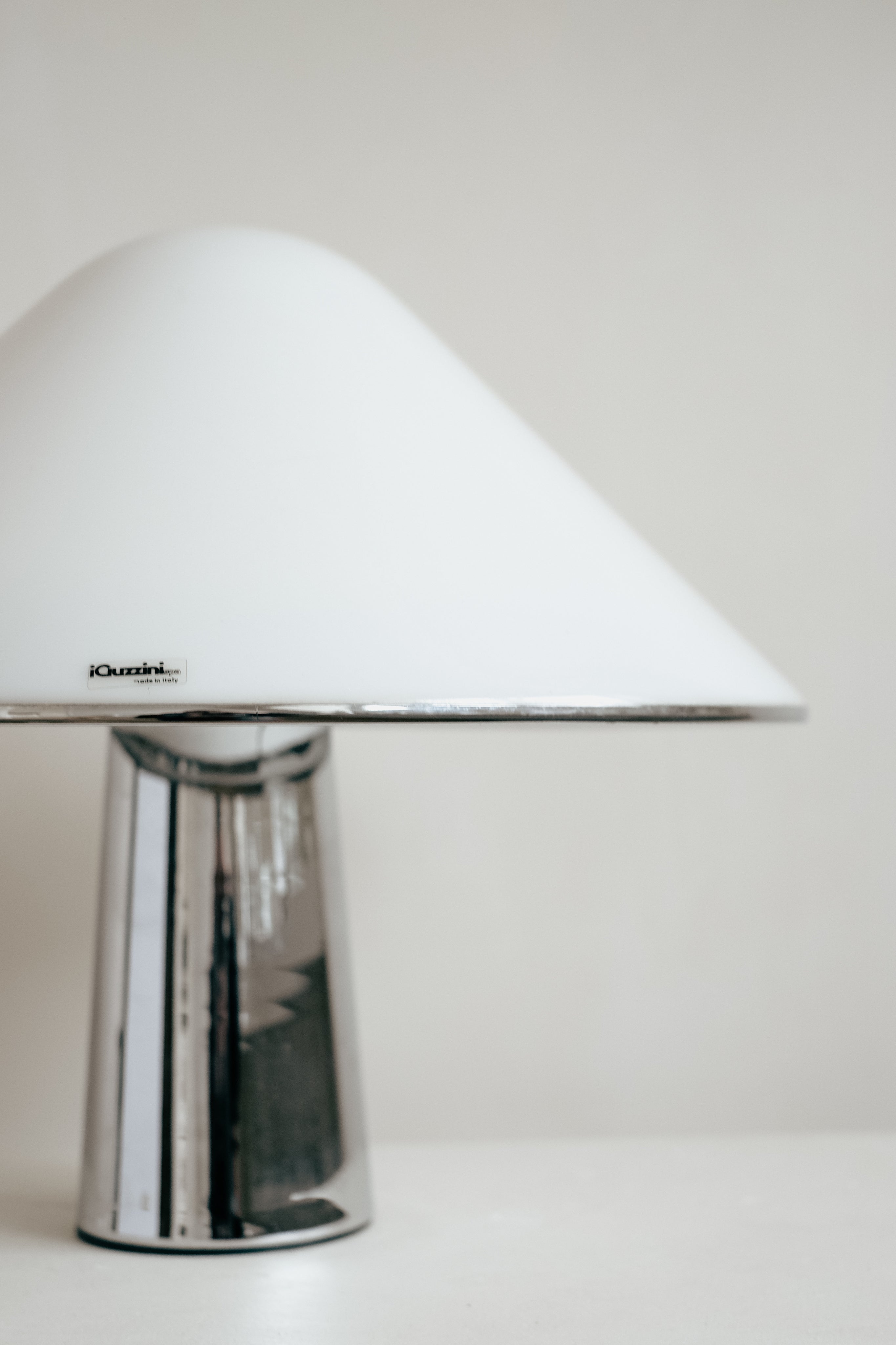 The Harvey Guzzini Elpis Table Lamp by septembre studios features a shiny chrome base and smooth white dome-shaped shade, displayed against a plain light background.