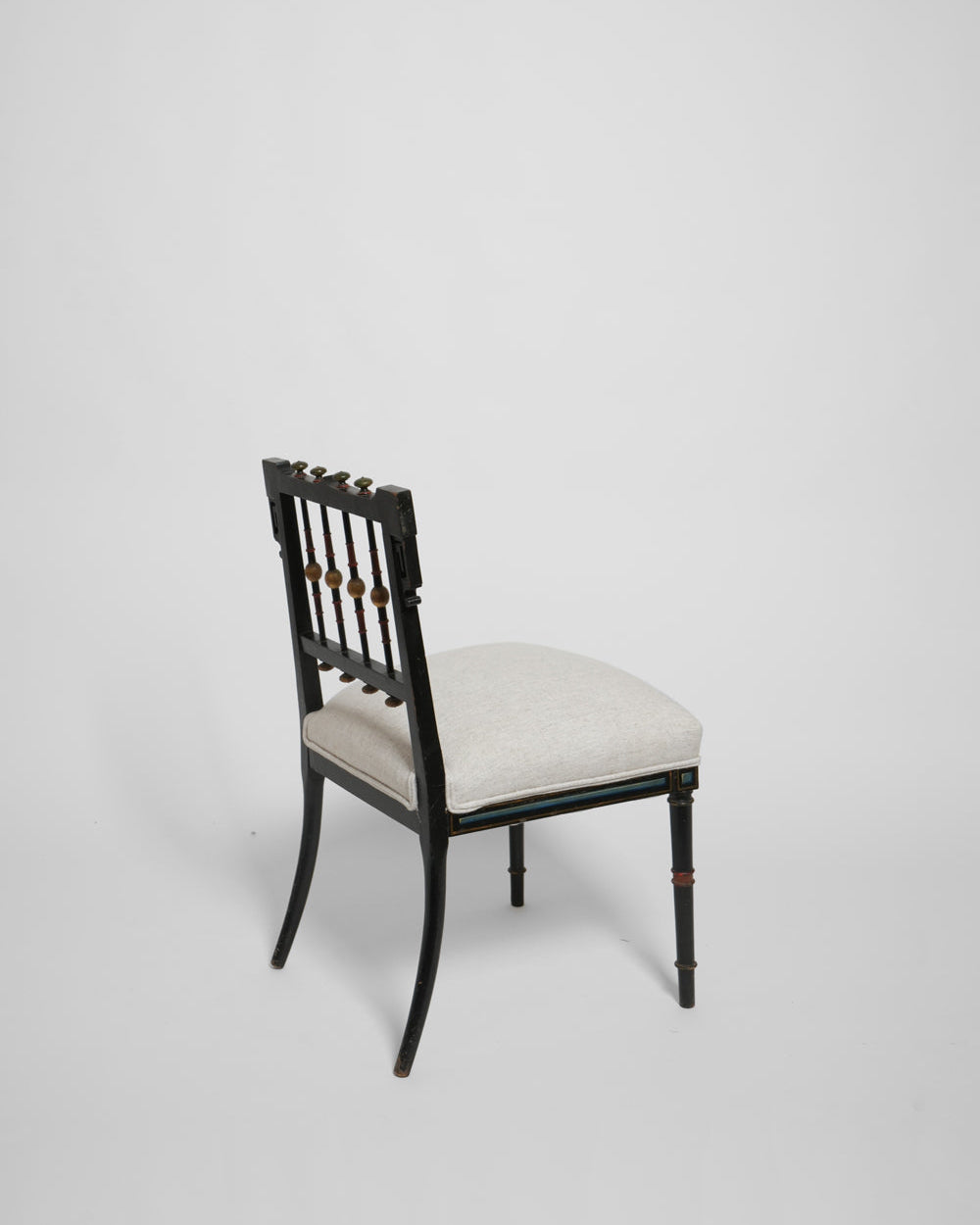 The Napoleon III Painted Armchair by Barracuda Interiors, 19th c., features a black frame, decorative spindle backrest, and light cushioned seat, shown angled against a plain light gray background.