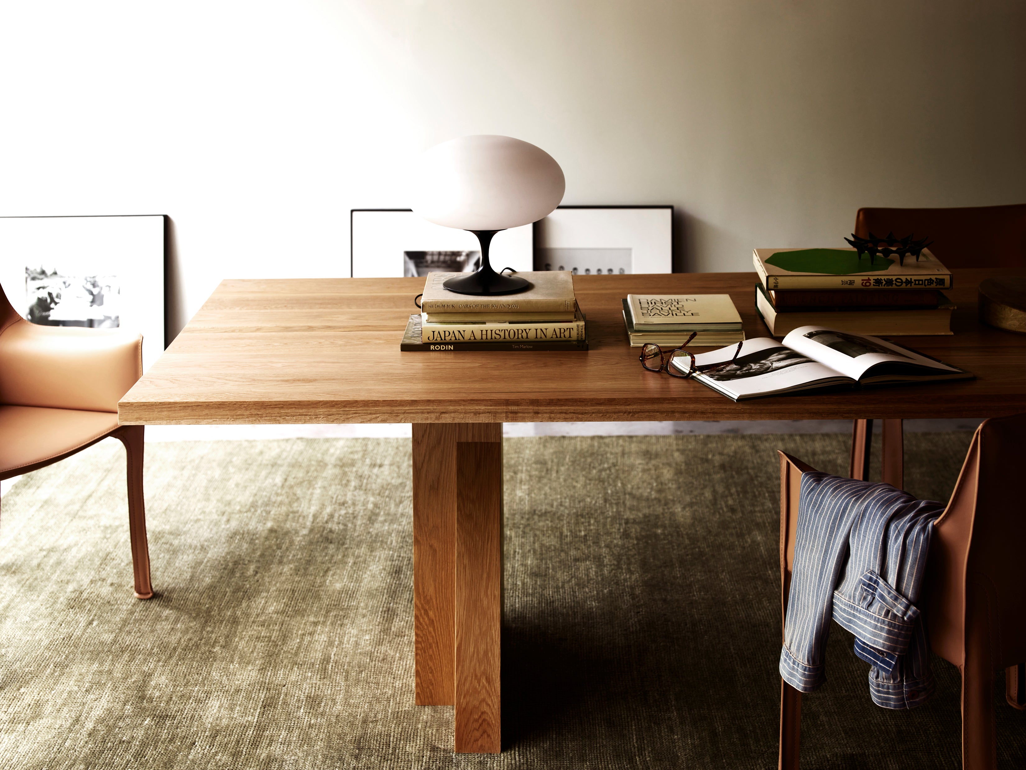 Elmyr Dining Table — angled view with oak surface and books