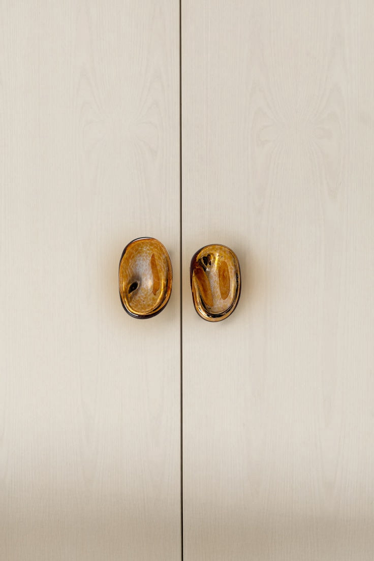 Knobs Collection Sculptures in Glass — close-up of amber glass knobs on cabinet