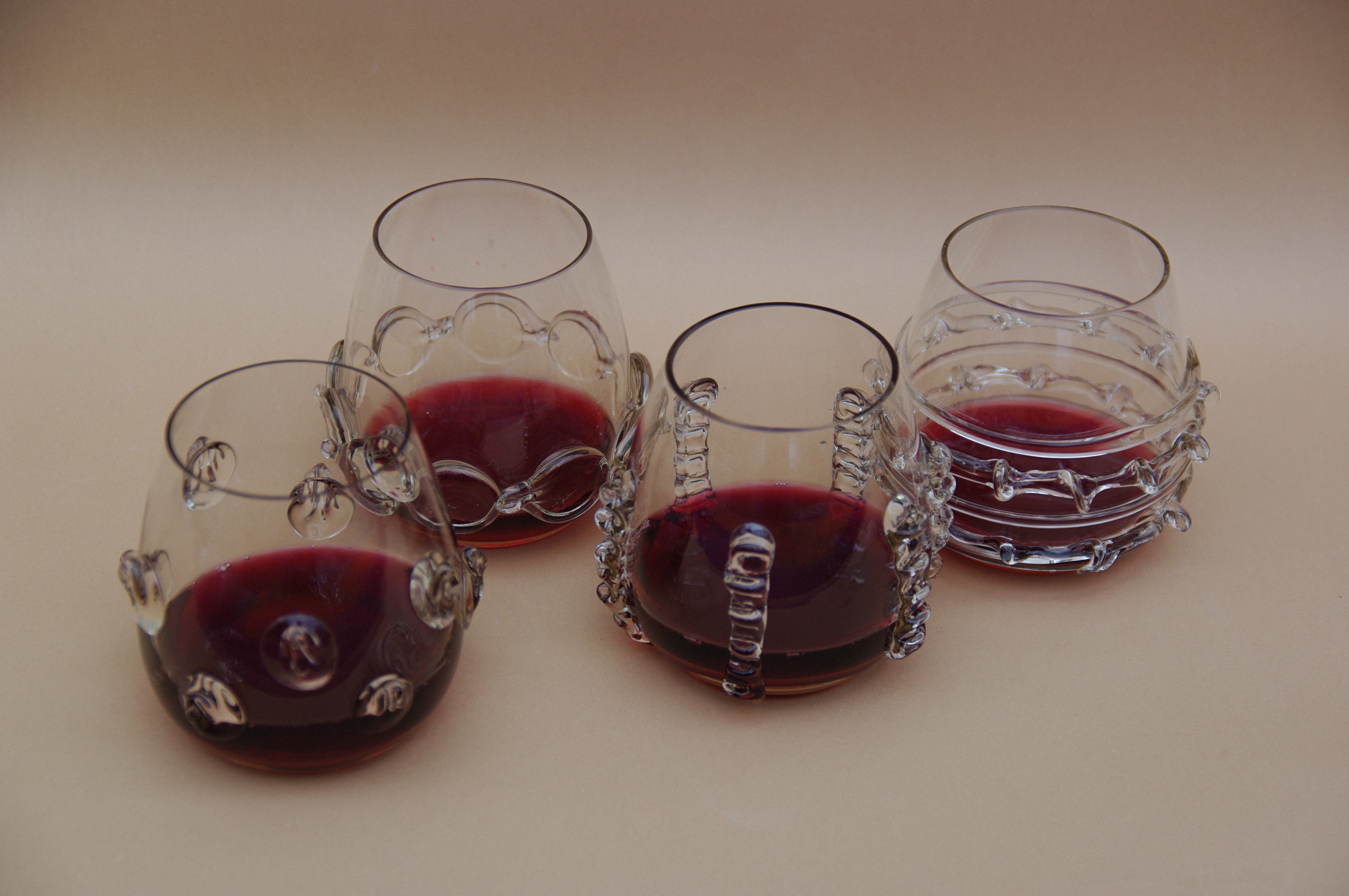 Contemporary Tumblr - Set of four handblown glass vessels - angled view with red liquid