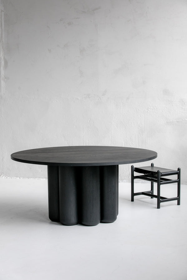 Ina Dining Table in Solid Wood — side angle showing round black top and sculpted base