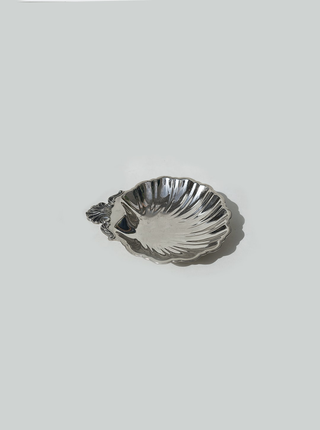 A stunning set of 4 small, silver-plated shell vide-poches by Les Objoies, each featuring a decorative handle and photographed on a light gray background—perfect as elegant decorative display pieces.