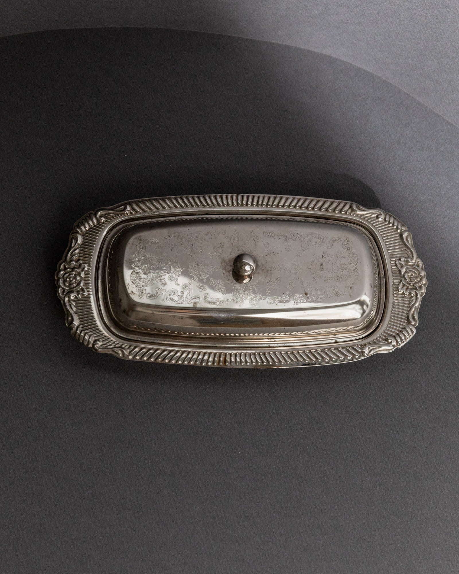 Previous slide Next slide Vintage 1970s Silver Plated Butter Dish, Engraved Ornamental — top view on dark background