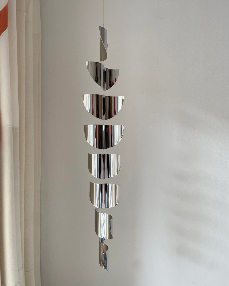 Polished steel spiral sculpture reflecting light by Studio Fie Paarup