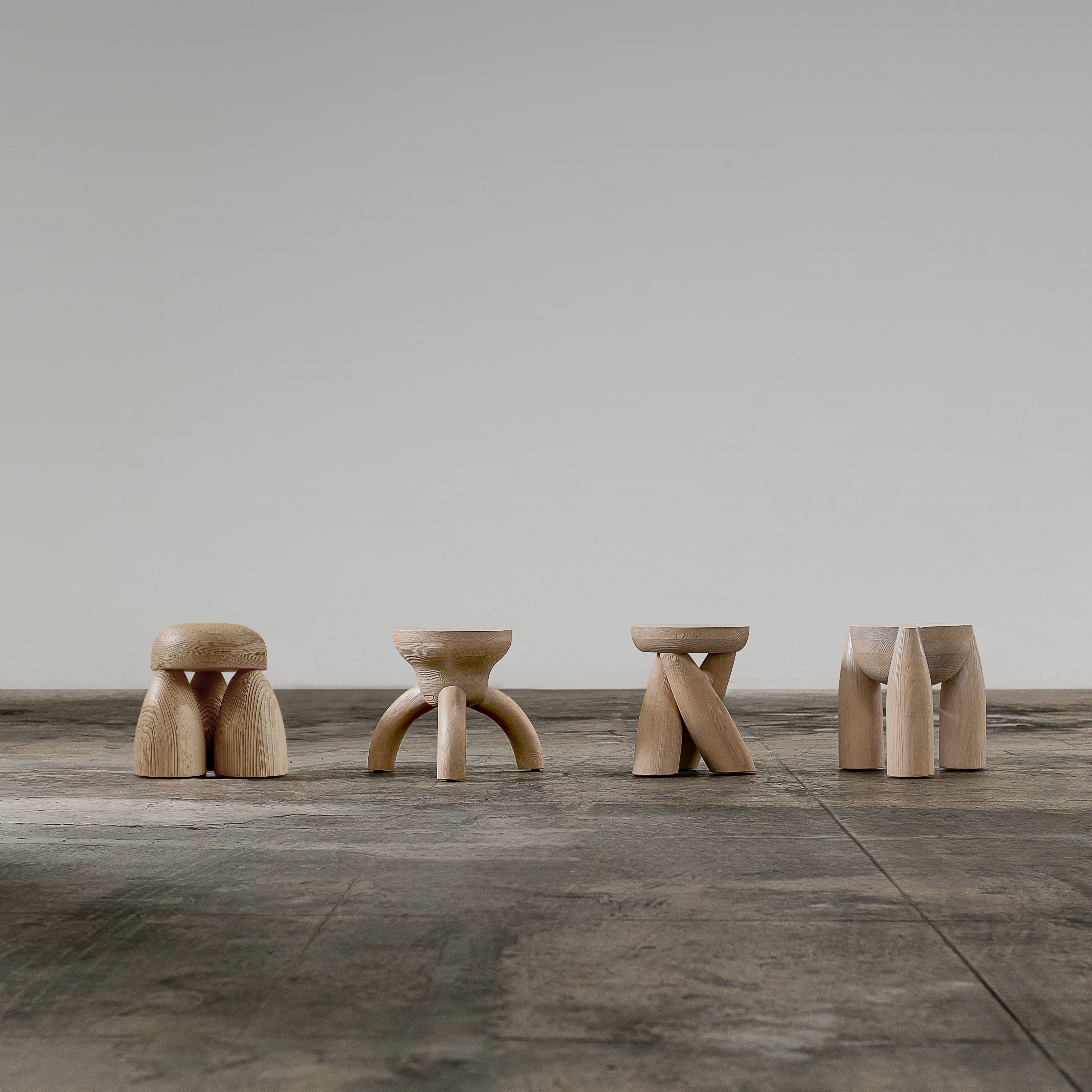 ELEMENTOS Set of Stools, sandblasted pine with black finish by Daniel Couttolenc — back view highlighting unique leg designs