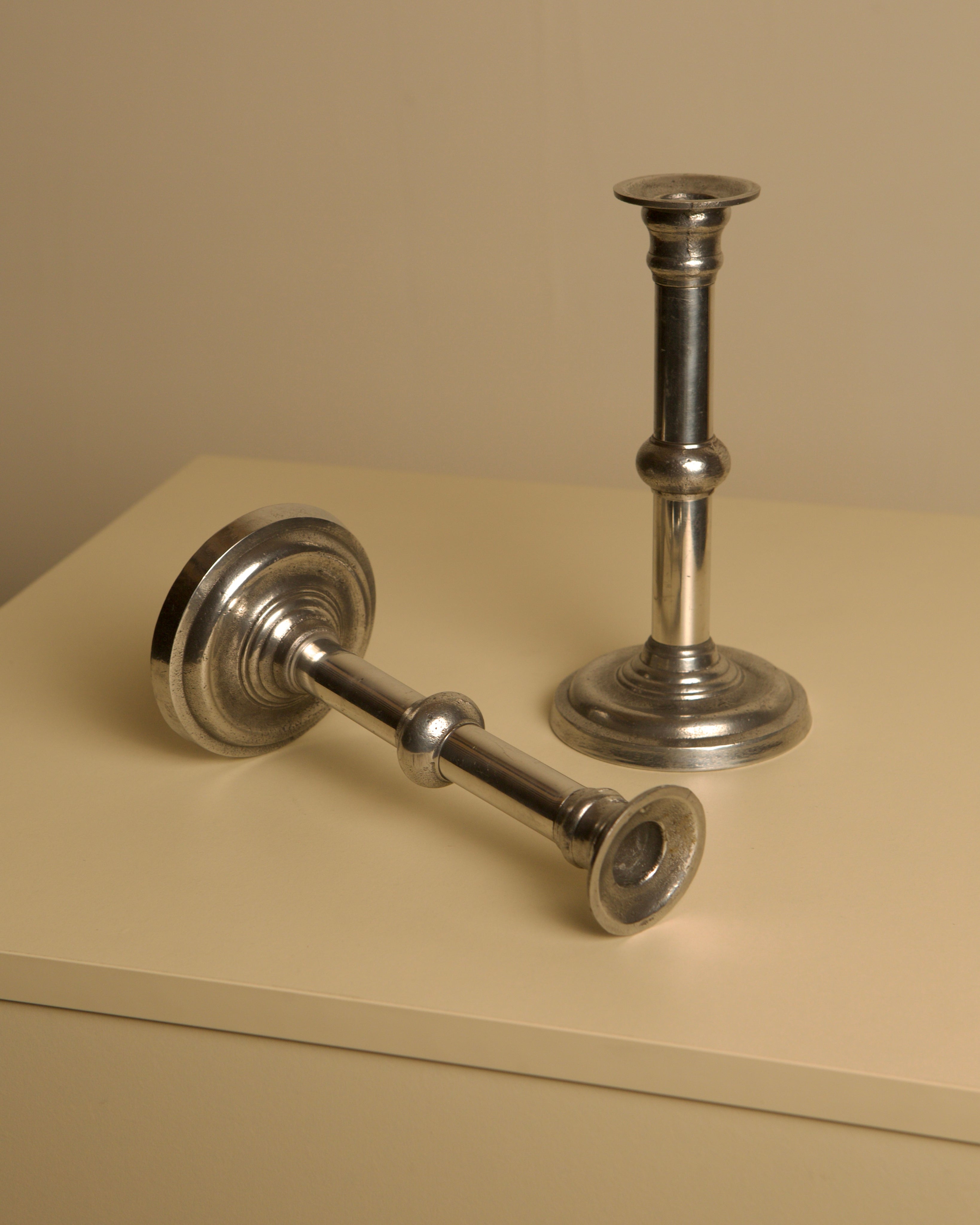 Pair of Italian Metal and Aluminum Candleholdersc80s — angled view on light-colored surface