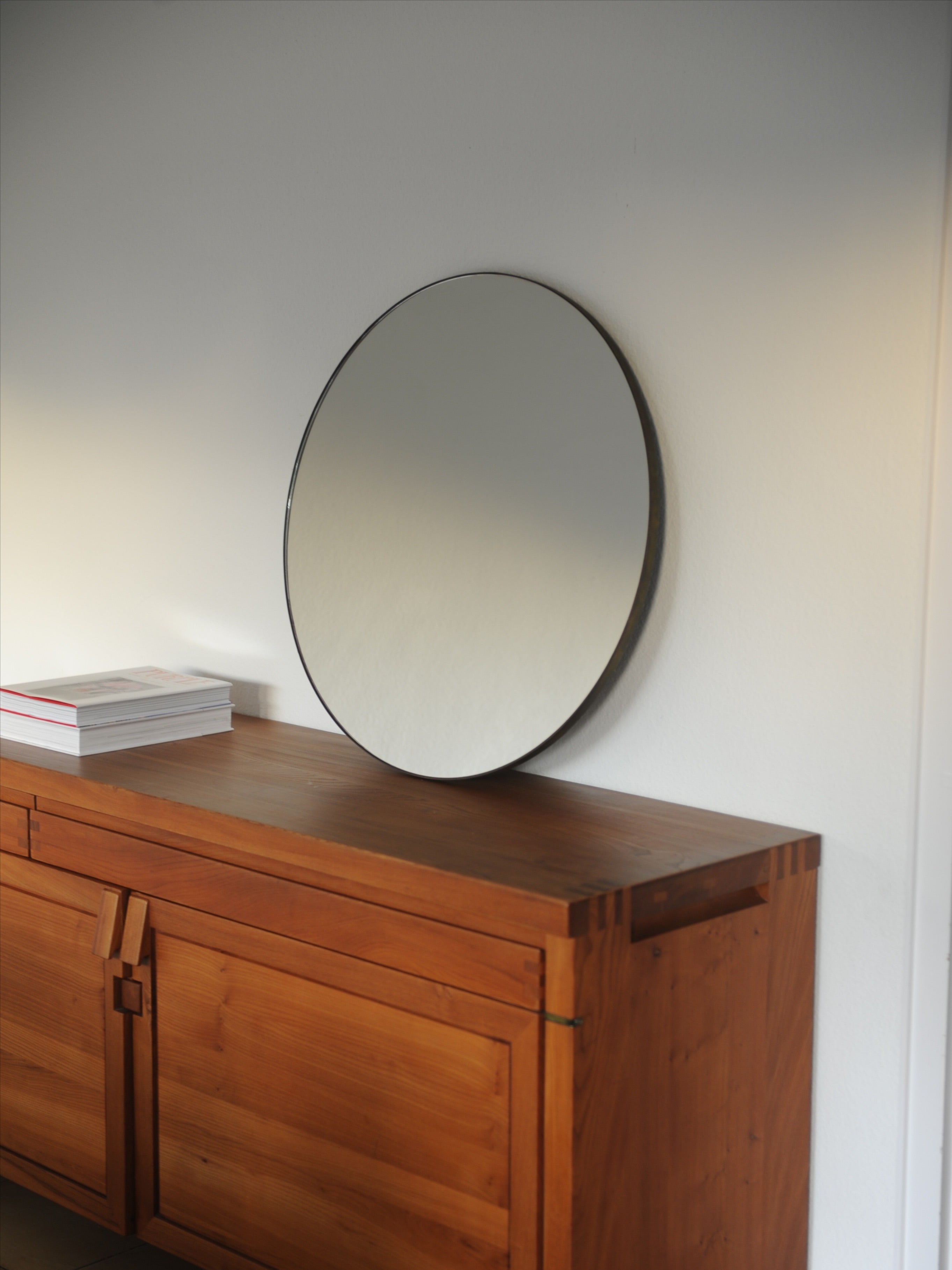 Mid-century circular mirror with black frame on teak sideboard