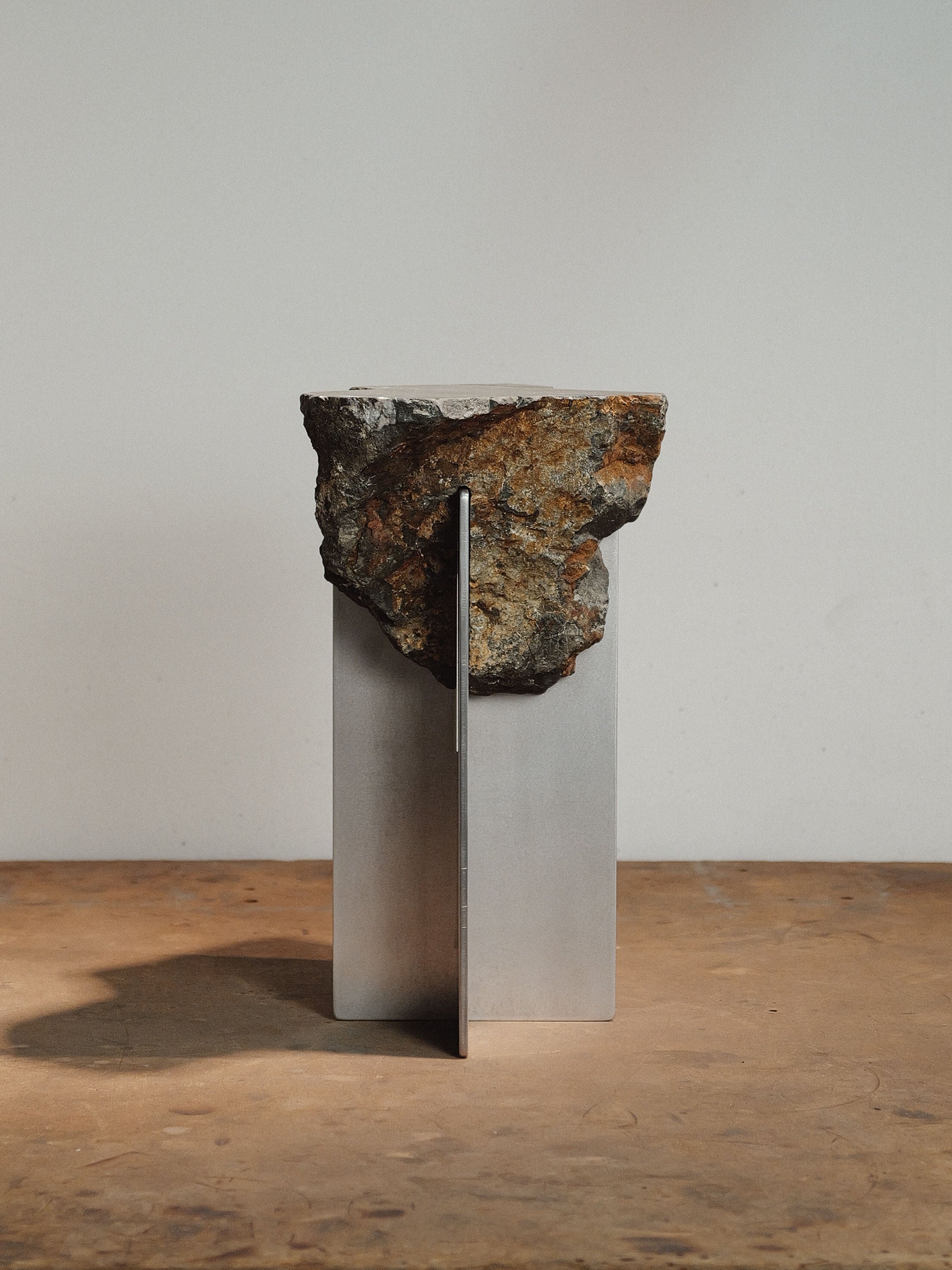 Hybrid Objects side table with raw stone balanced on metal pedestal