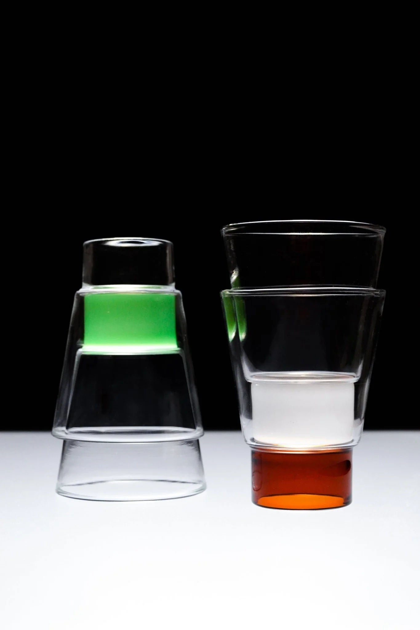 Podio' Glass - Amber — stacked with clear and green glasses on black background