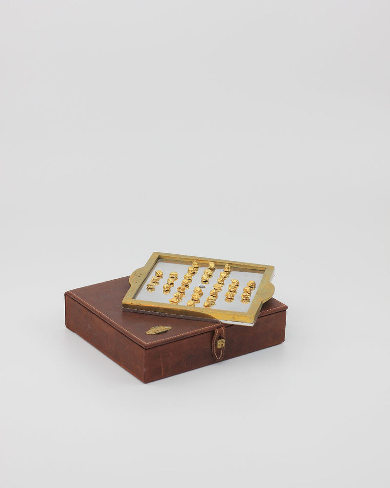 Solitario Inglés — close-up of brass game pieces on leather box