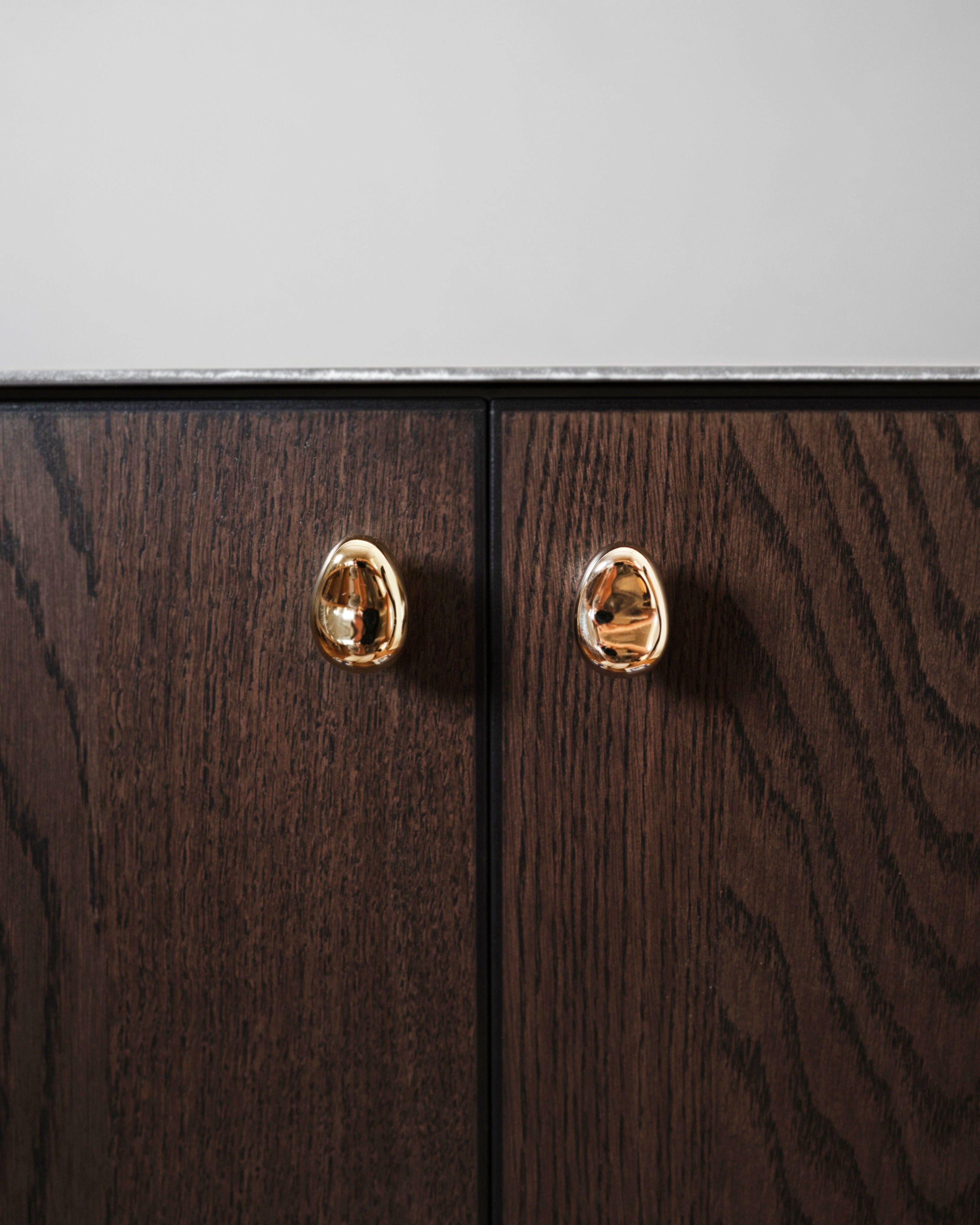 Rud Knob - Brass — close-up of brass knob on dark wood cabinet