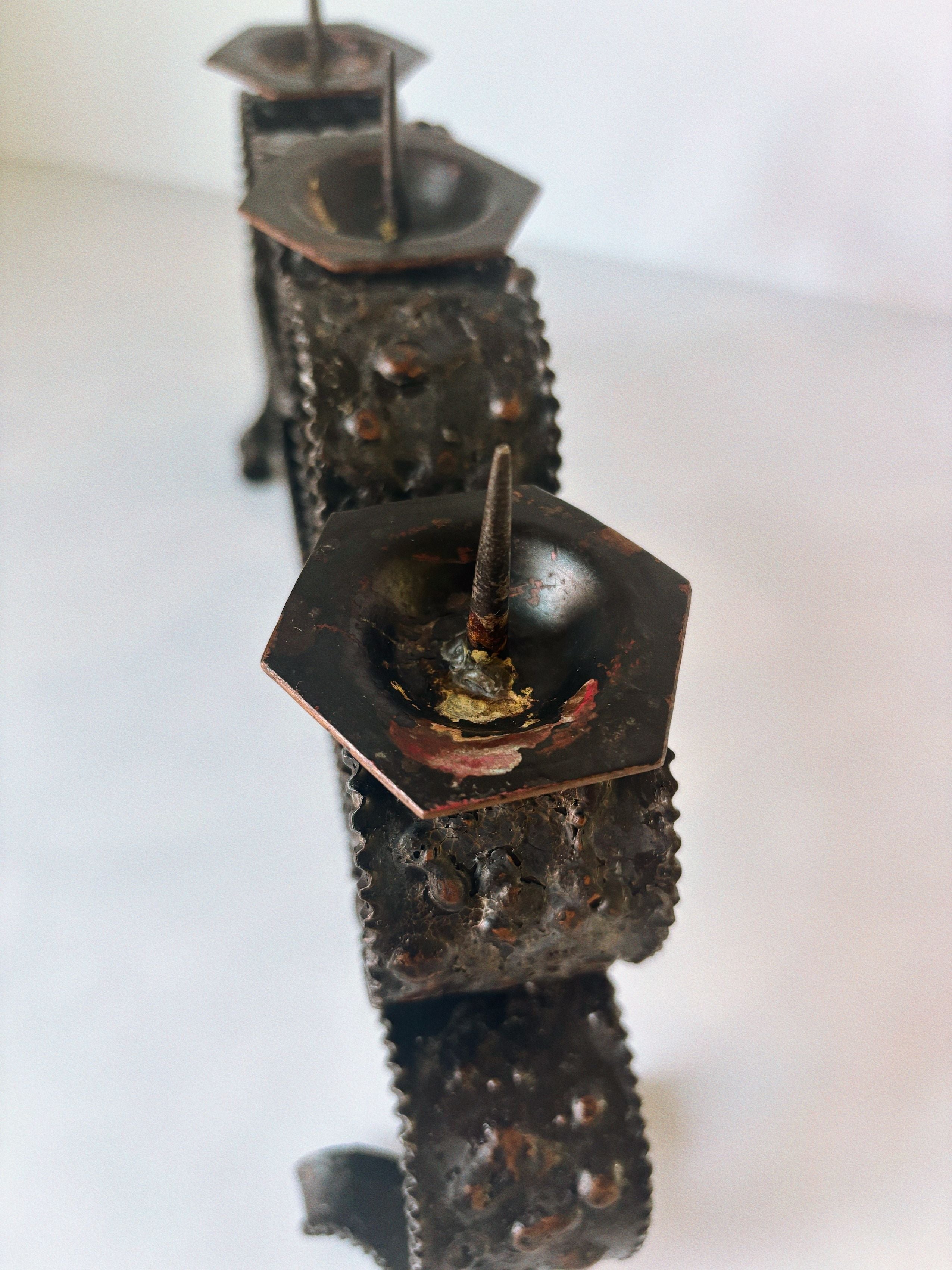 Polish metal candleholder with ornate textured base and curved arms