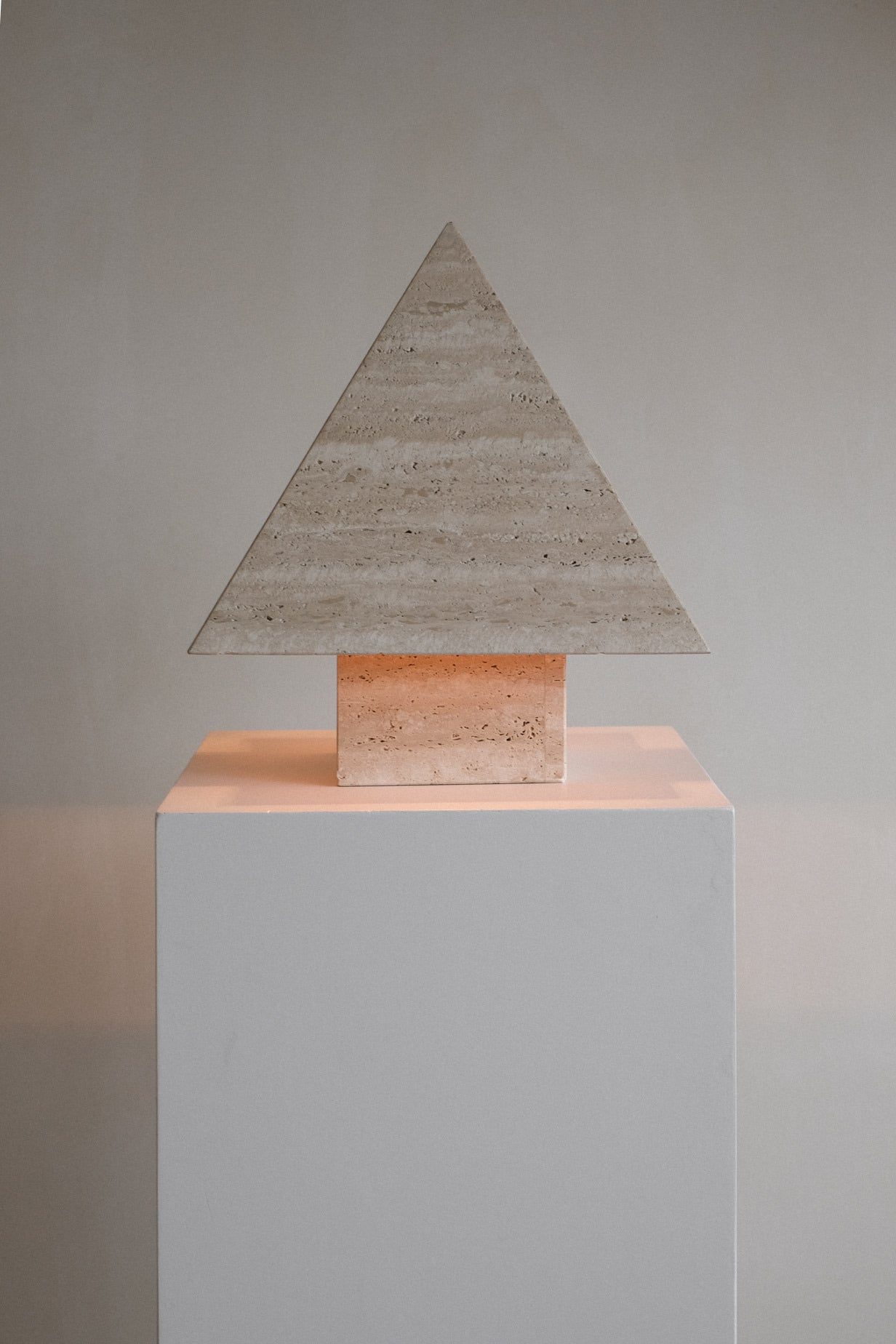 Travertine Pyramid Table Lamp — front view on white pedestal