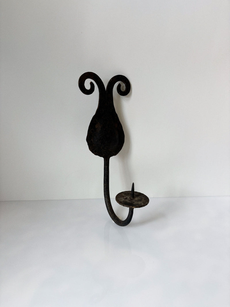 Hand-forged iron wall sconce with curved scrollwork detail