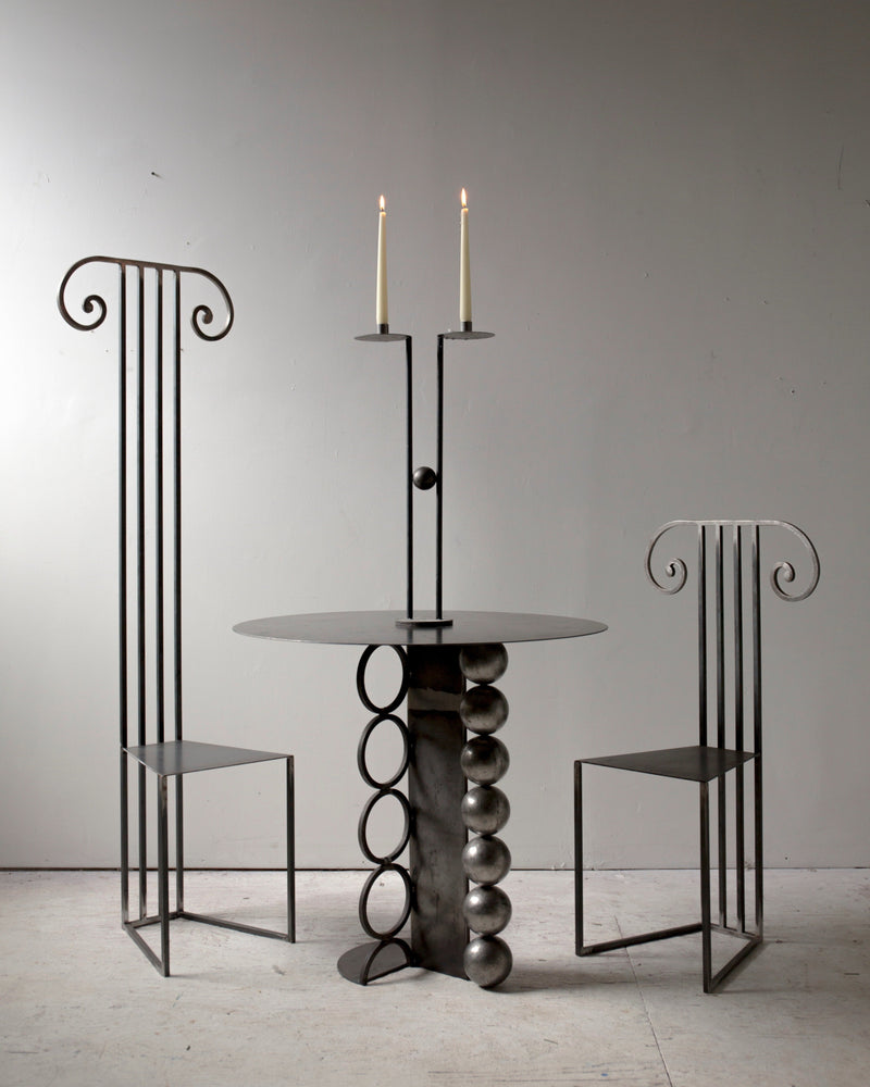 Modern black metal Column chairs with sculptural table and lit candles