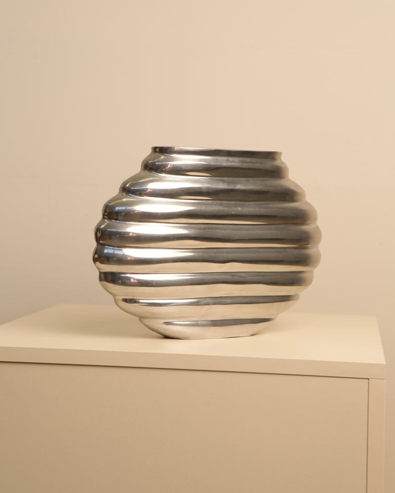Ribbed silver aluminum vase with horizontal grooves, side view