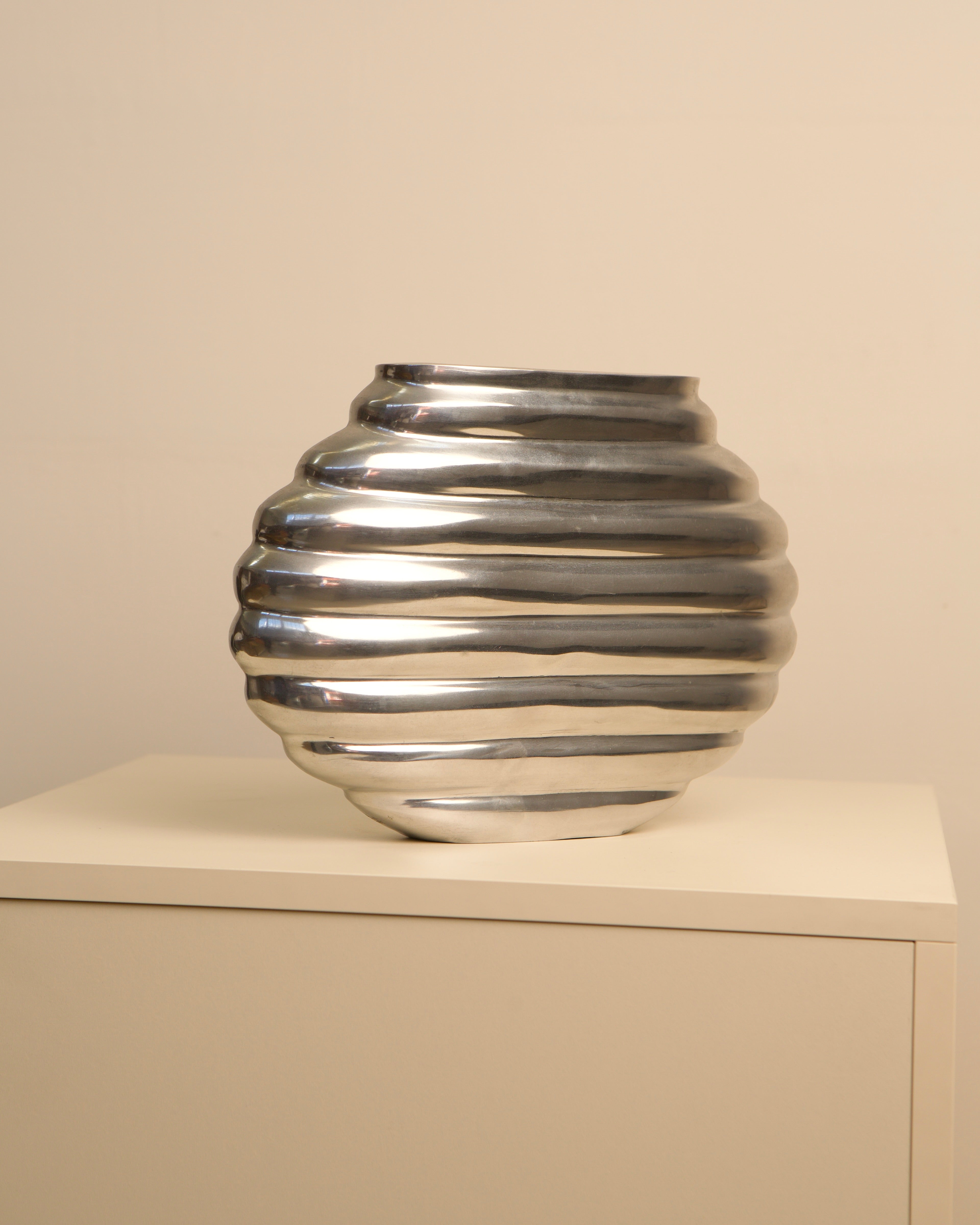 Ribbed silver aluminum vase with horizontal grooves, side view