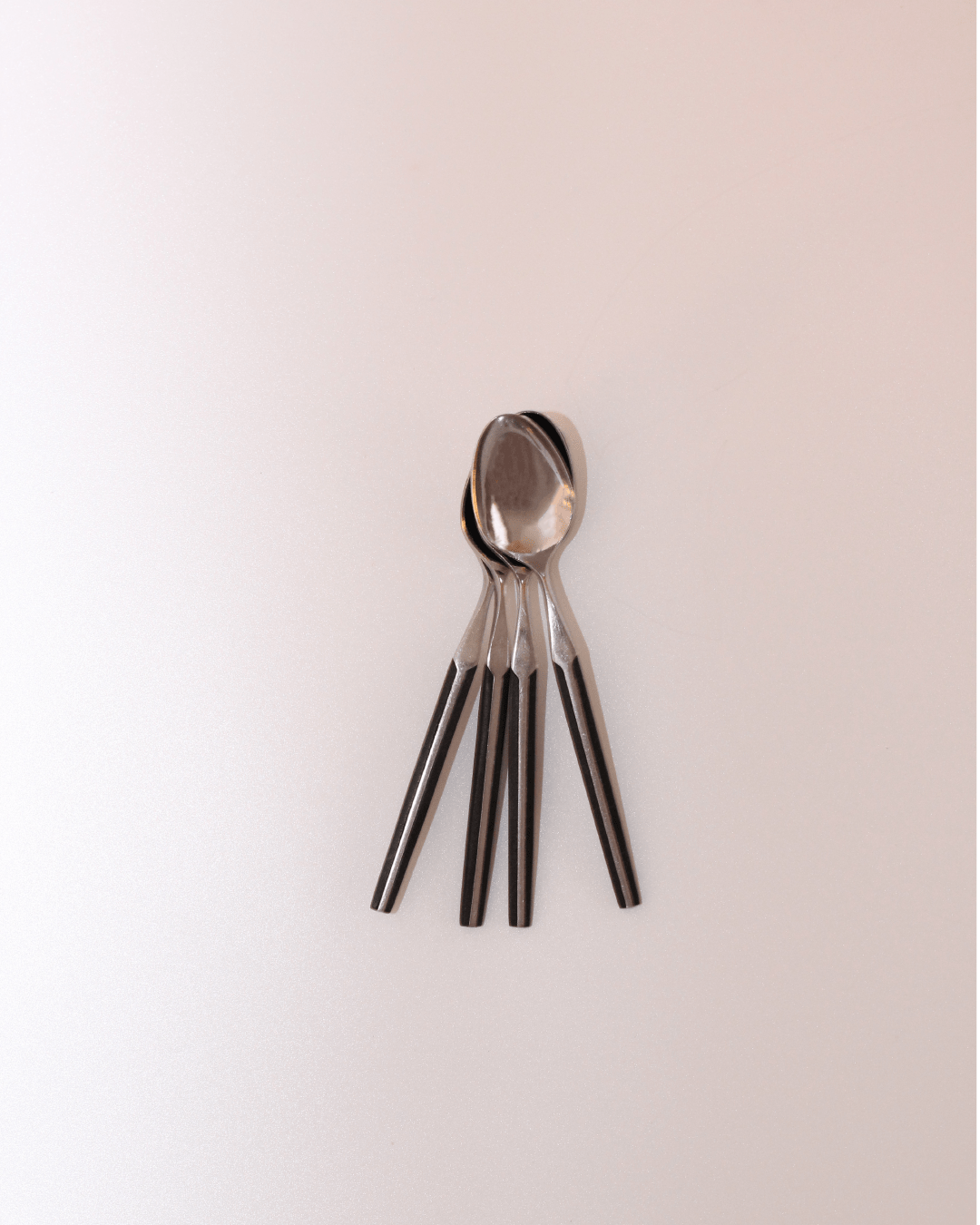Mid-Century Cutlery — top view of stainless steel spoons on light surface