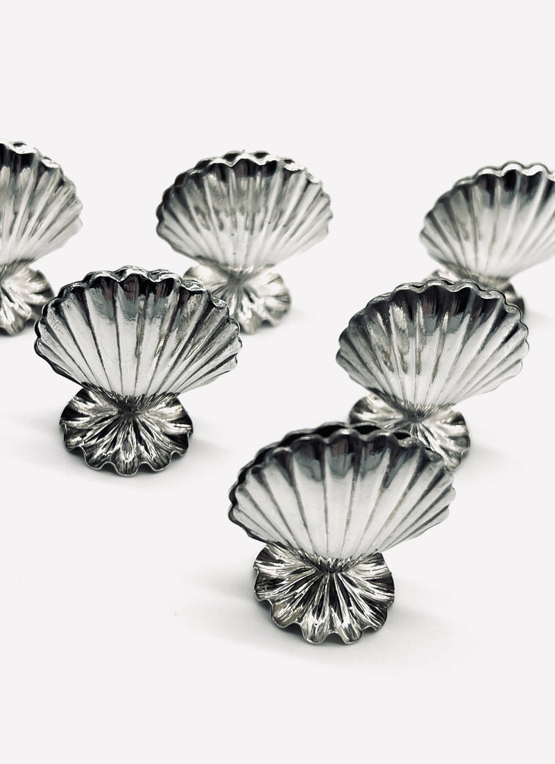Set of vintage silver shell-shaped card holders arranged on white surface