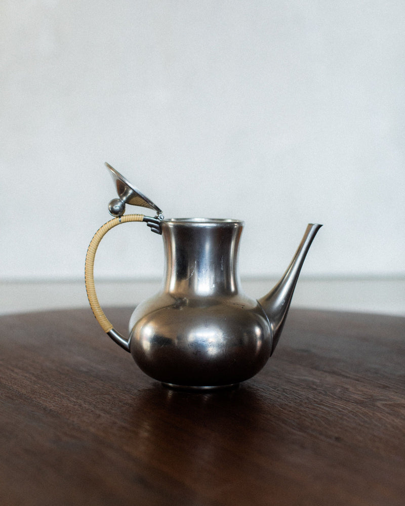 Polished pewter Art Deco teapot with rattan-wrapped handle
