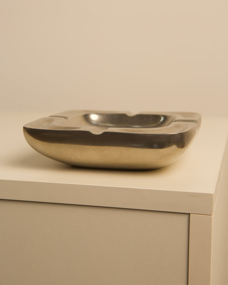 Golden aluminum square ashtray on cabinet, detail view of vintage 70s design