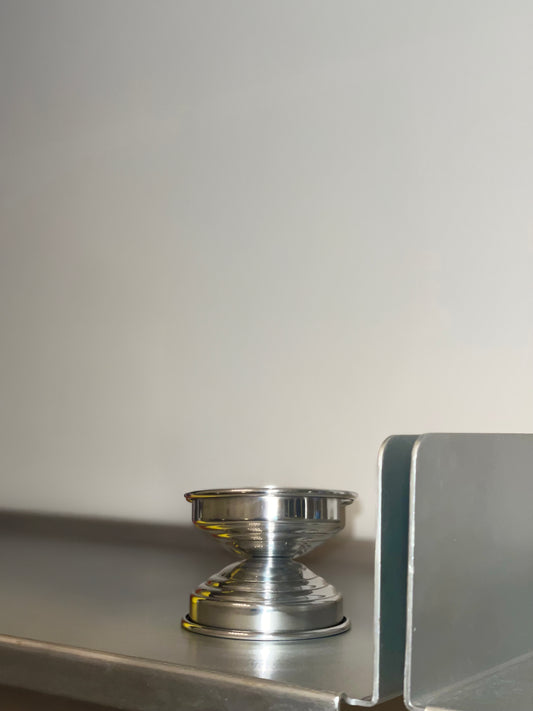 Metal Candle Holders in Polished Aluminum — angled view on metal shelf