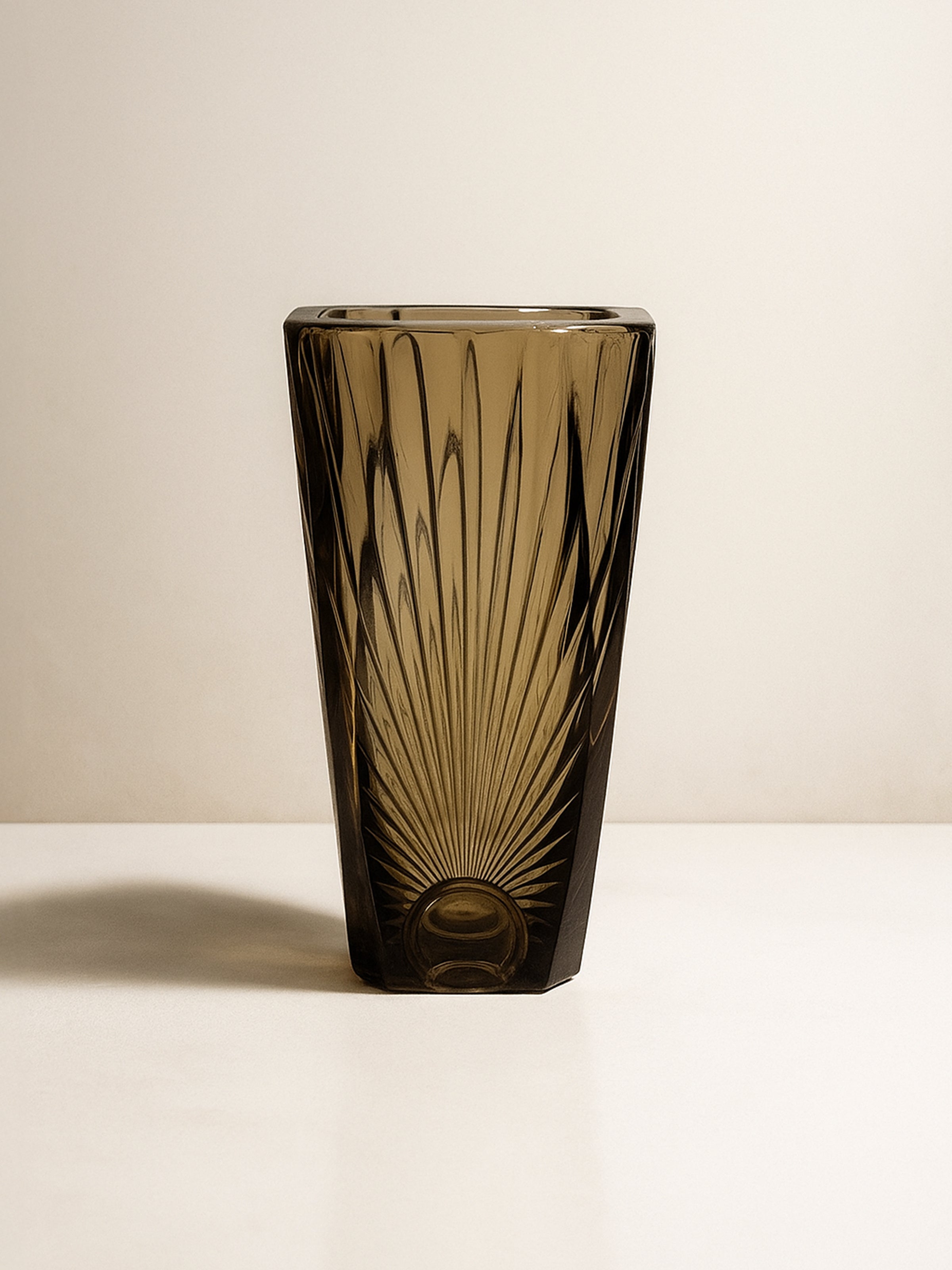 The Art Deco Smoked Glass Vase - 1930s by Dodo Vintage features a tall form and etched sunburst pattern, capturing French Art Deco elegance as it rests on a light surface against a plain background.