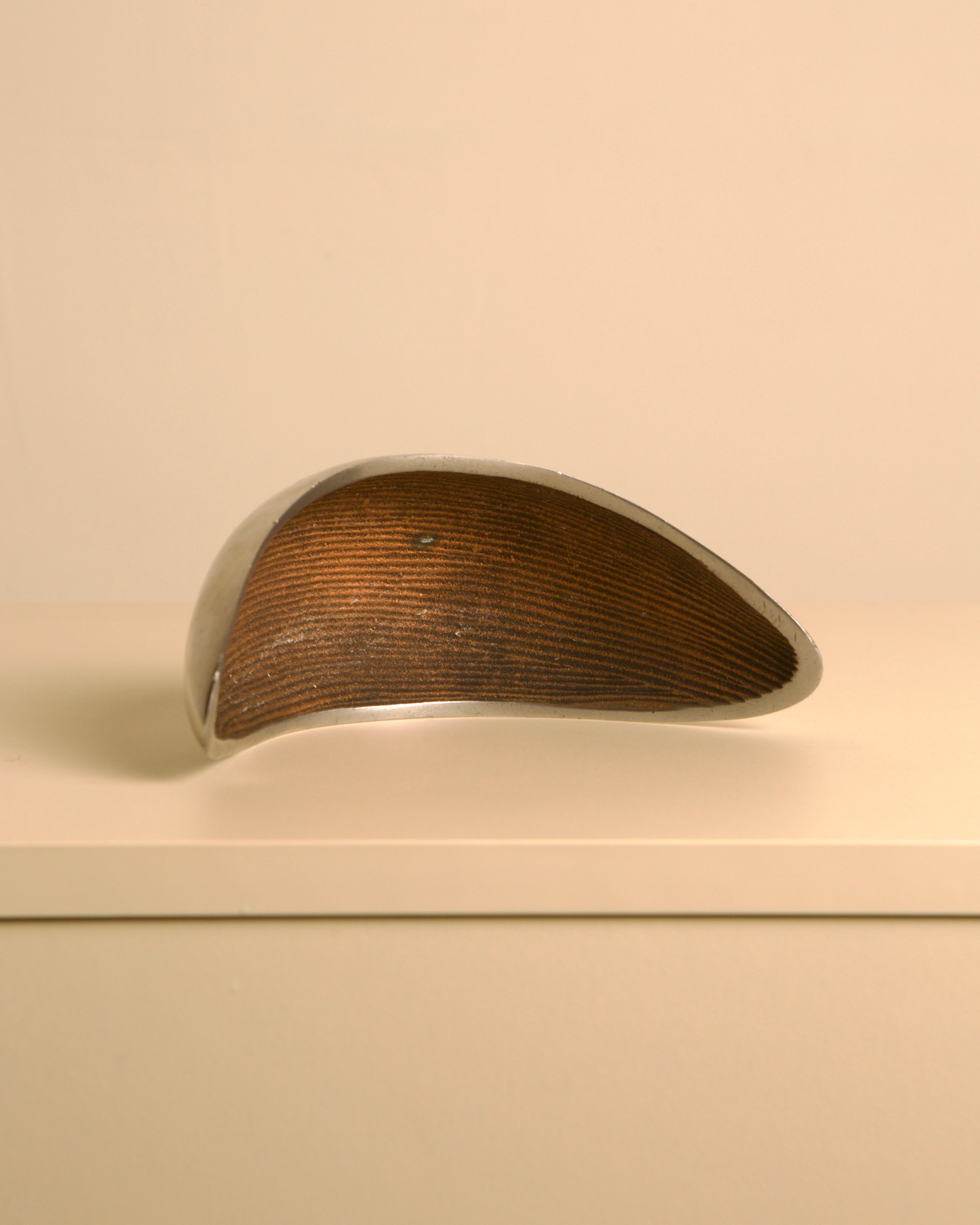 Italian "Croissant" Trinket Tray in cast aluminum — side view on neutral shelf