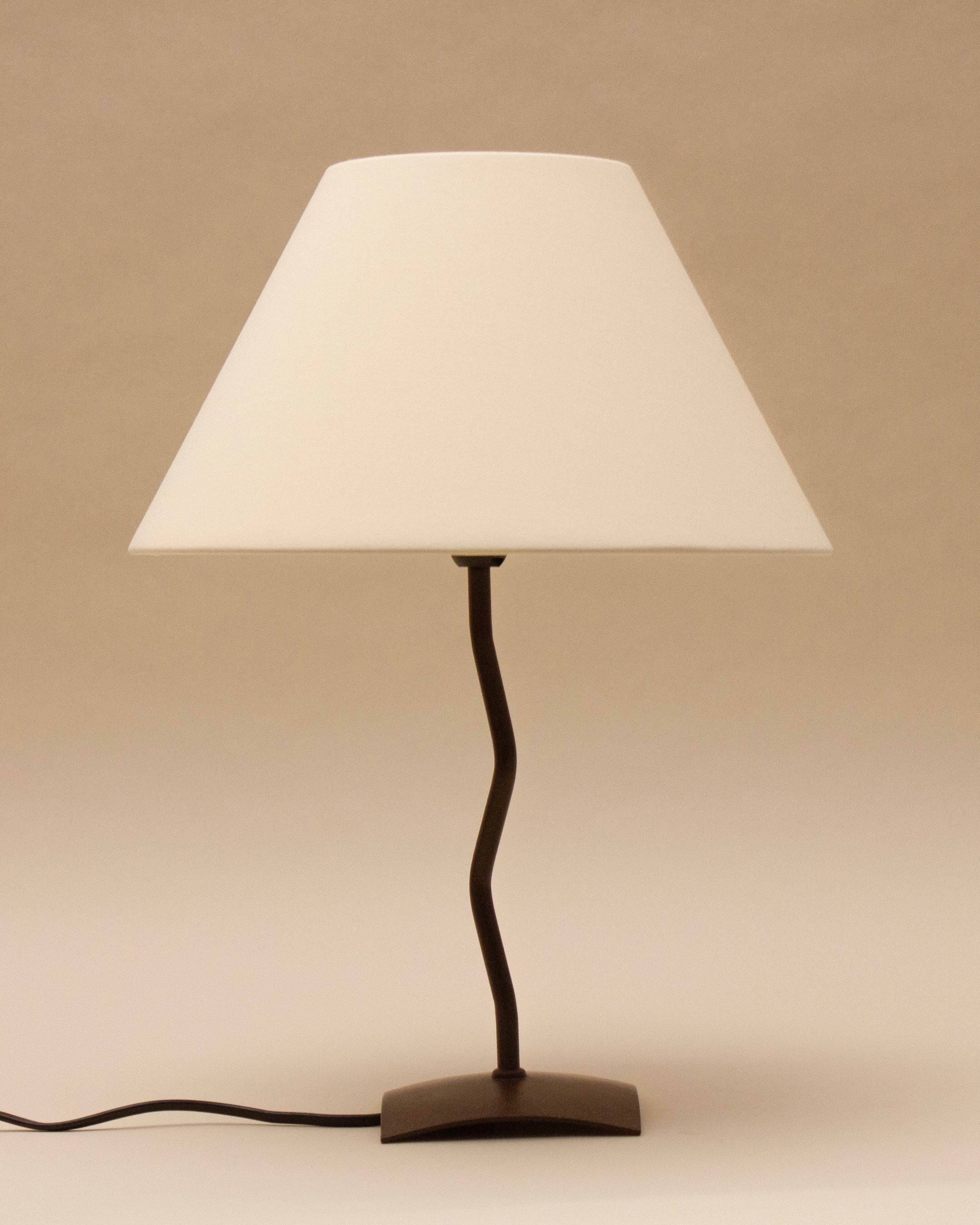 The SÒLER BILBAO TABLE LAMP features a black metal base, twisted stand, and vintage white shade. It sits on a flat surface with its cord visible, set against a plain beige background.