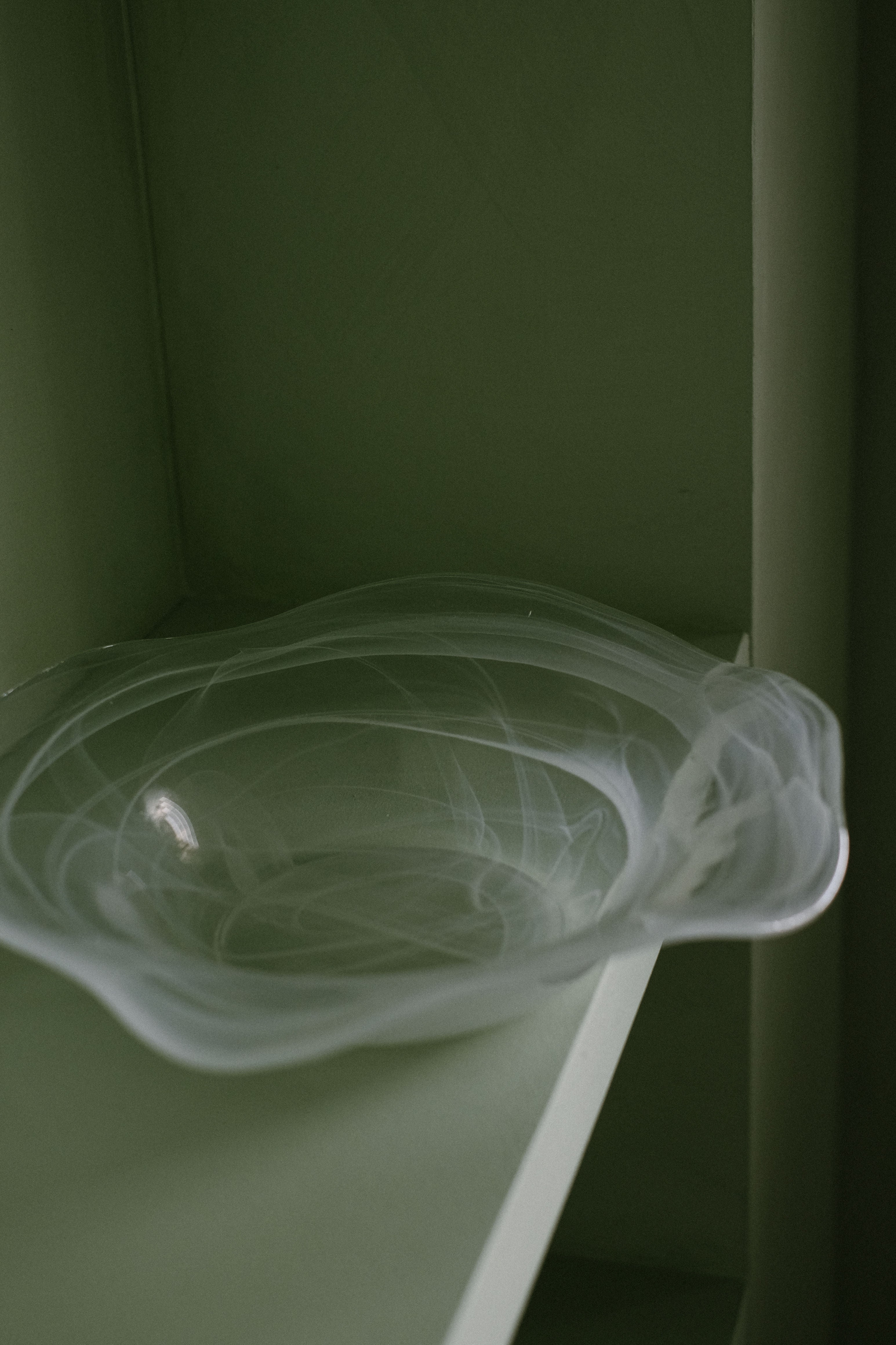 Swirl Glass Bowl — angled view on green shelf