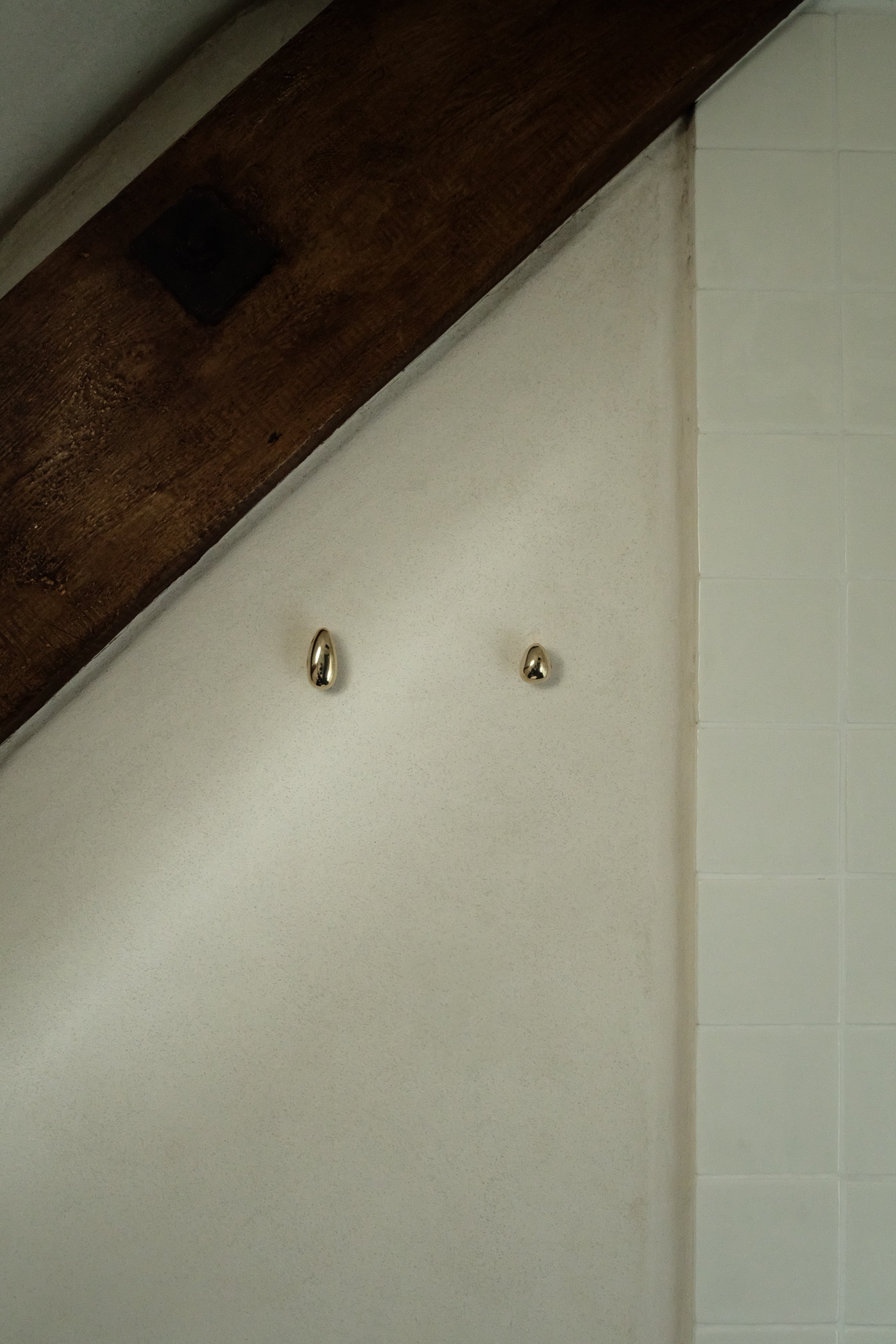 MOMI Cabinet Knob/Wall Hook Short Mini — close-up of shiny brass knobs on textured wall