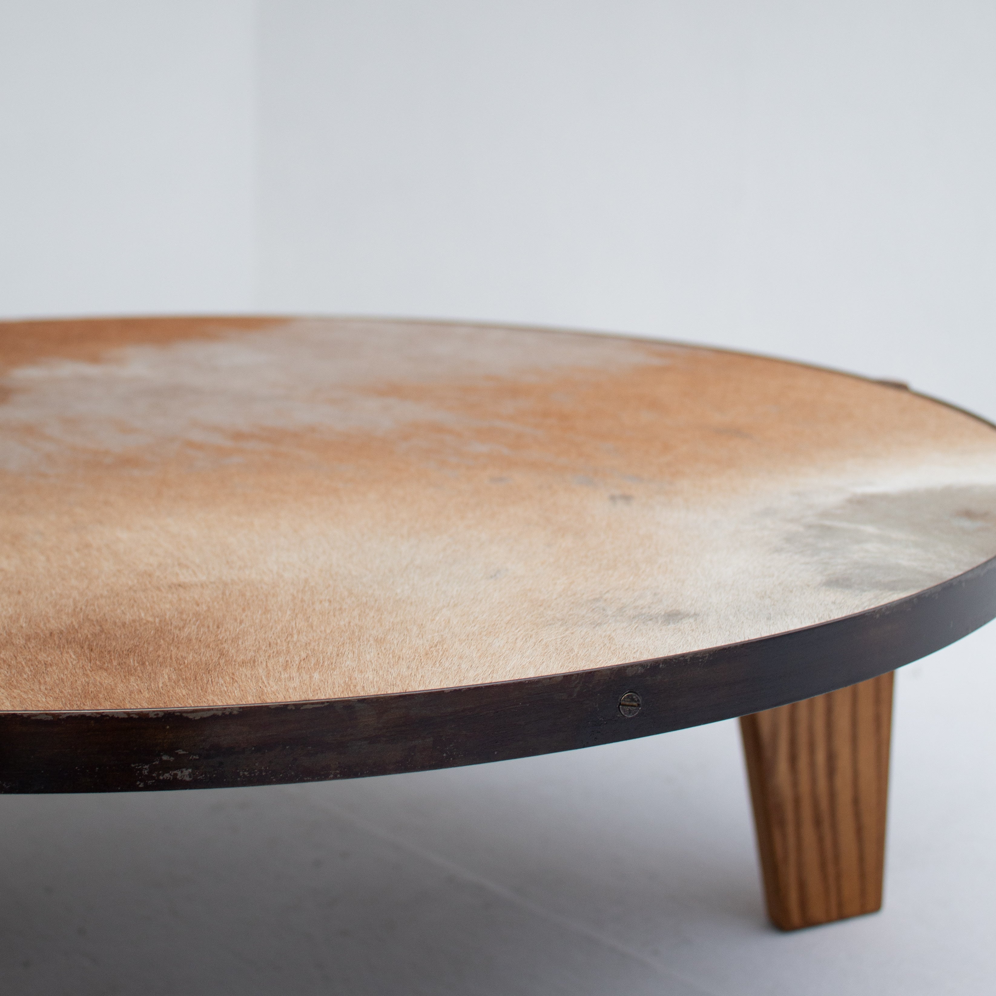 2 Coffee Tables in Wood and Cowhide — close-up of round table surface