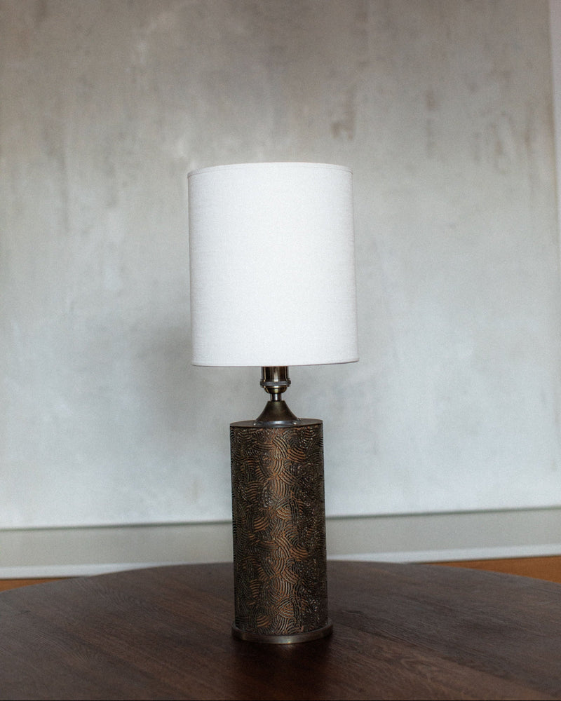 Monolithic cylindrical table lamp with textured bronze base and white shade