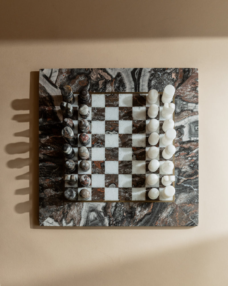 Vintage marble chess set with carved pieces on checkered stone board