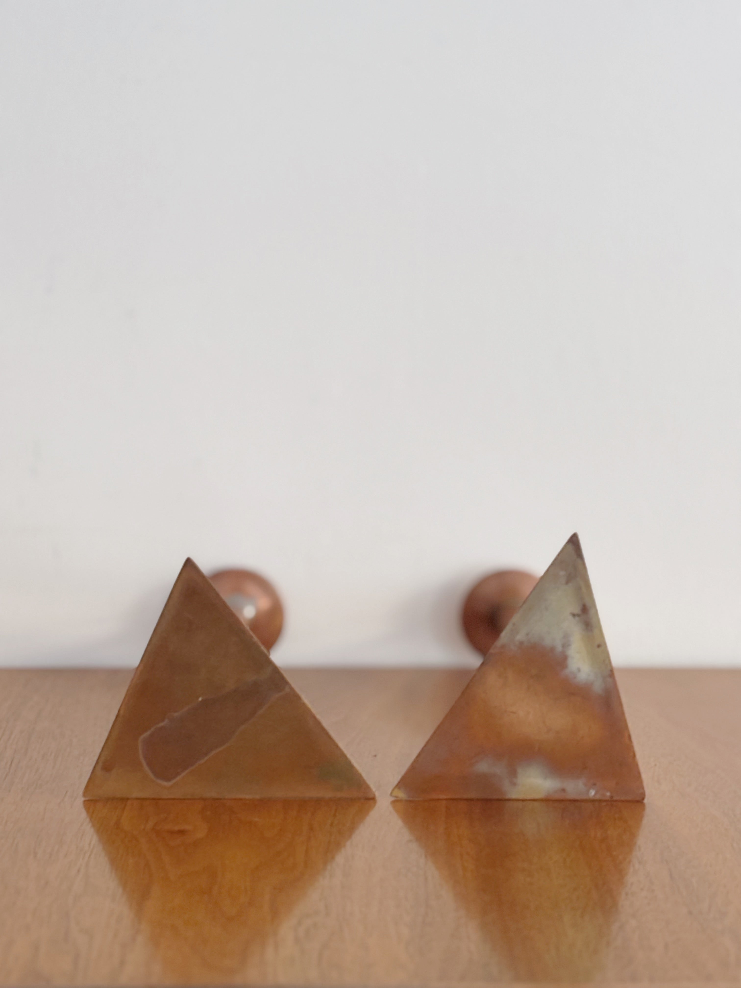 2 Copper Postmodern Candlesticks — side angle showing triangular bases on wooden surface