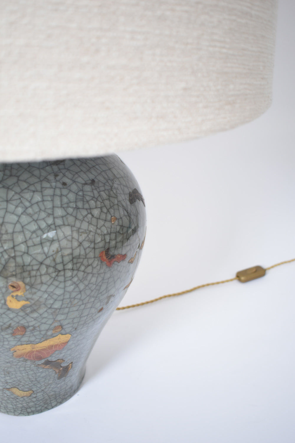 A close-up of the Barracuda Interiors Chinese Celadon and Gold Lamp, XIXth c., with crackled glaze, painted floral designs, a beige fabric shade, and an inline switch cord, shown against a white background.